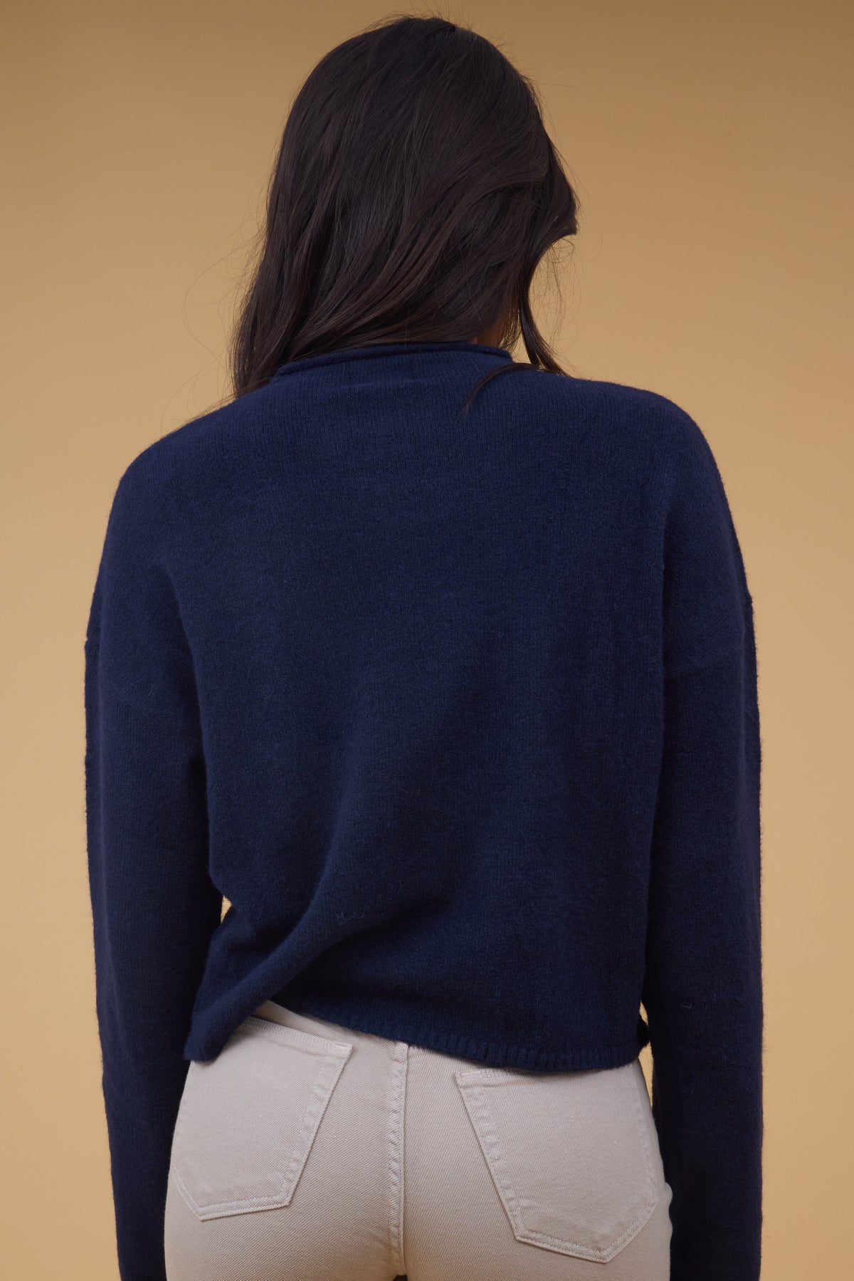 Back view of a woman wearing a long sleeve navy sweater.