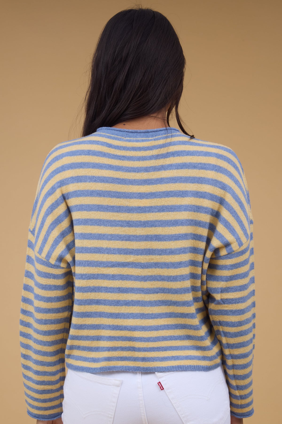 Back view of a woman wearing a blue & yellow stripe cardigan with drop shoulders and long sleeves.