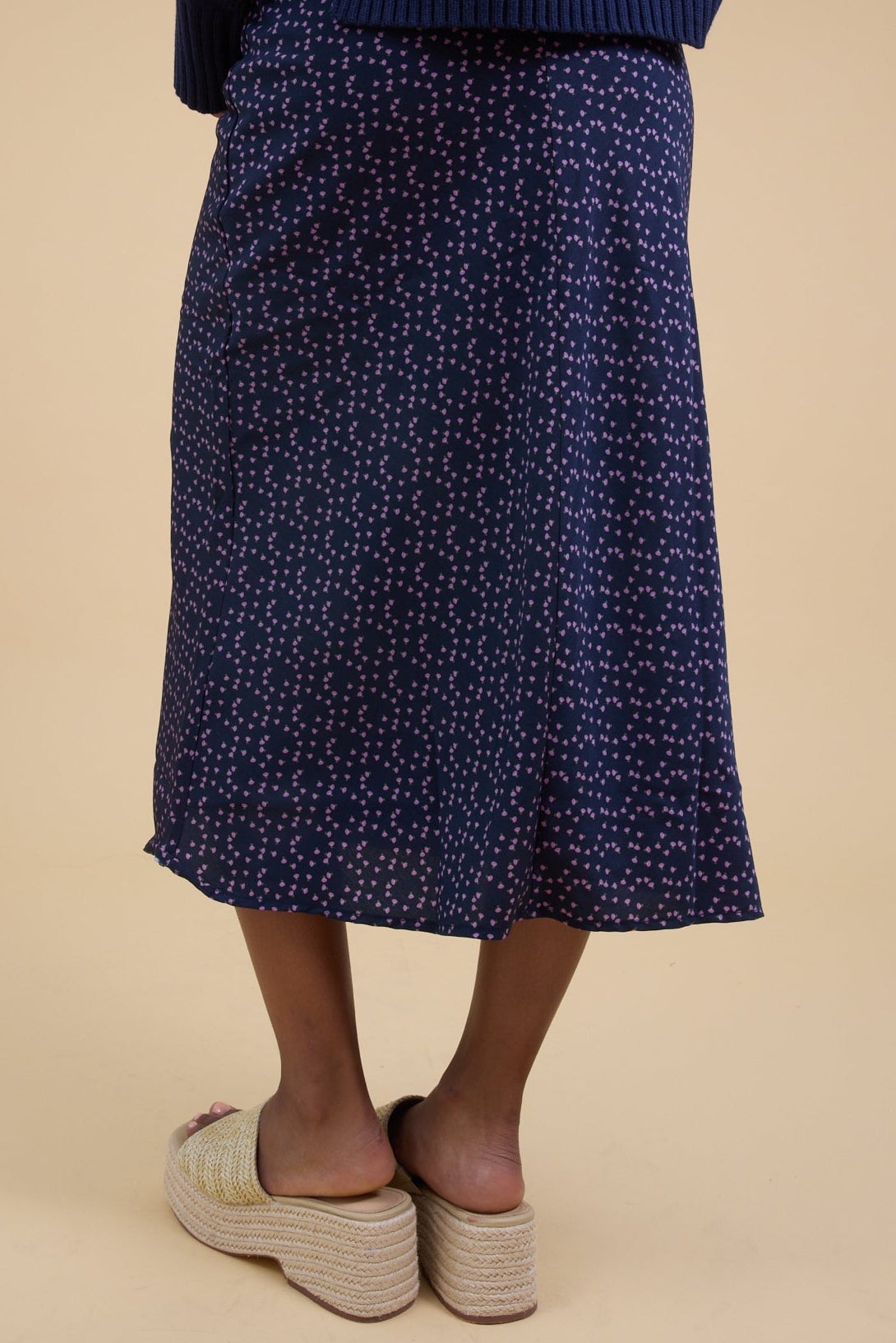 Back view of a young woman wearing a navy floral A-line midi skirt.