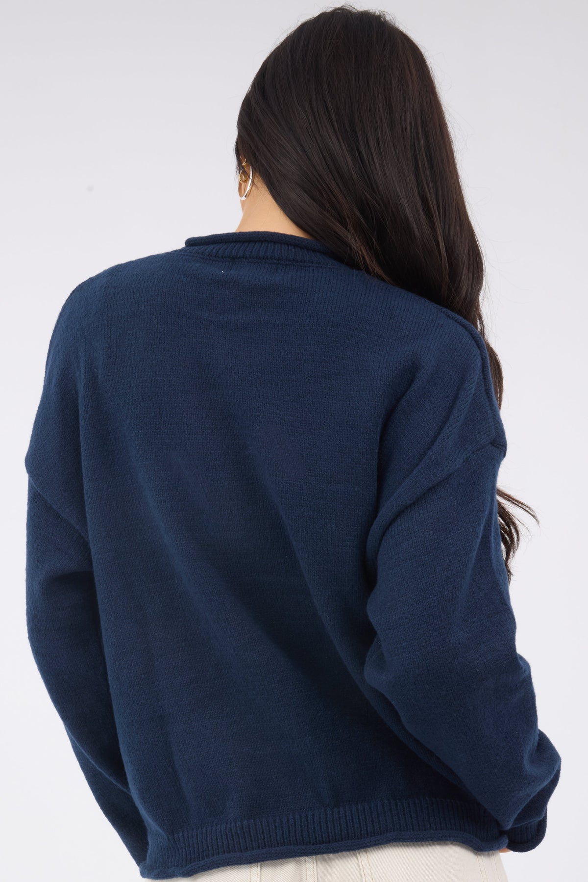 A back view of a woman wearing a loose fitting navy sweater with long sleeves.
