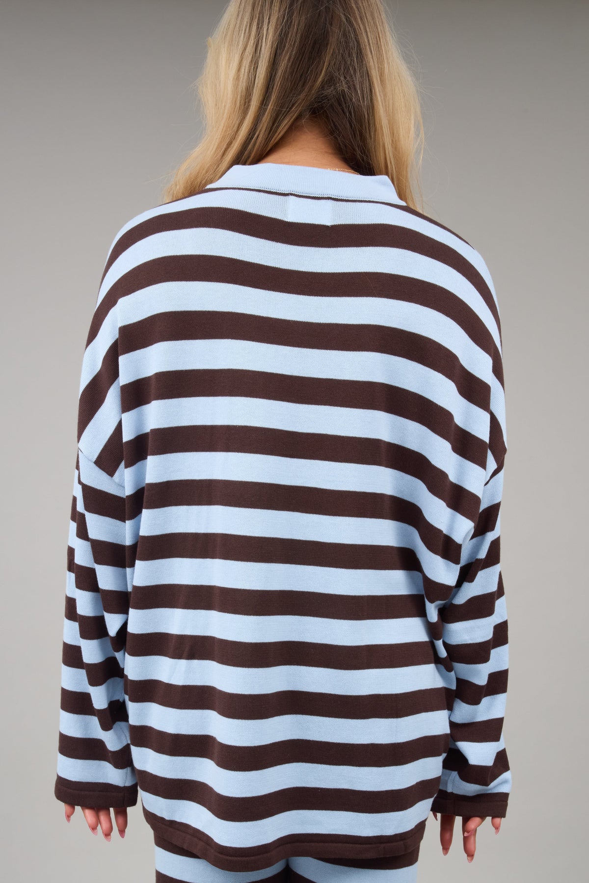 Back view of a woman wearing a a loose fitting brown & light blue top.
