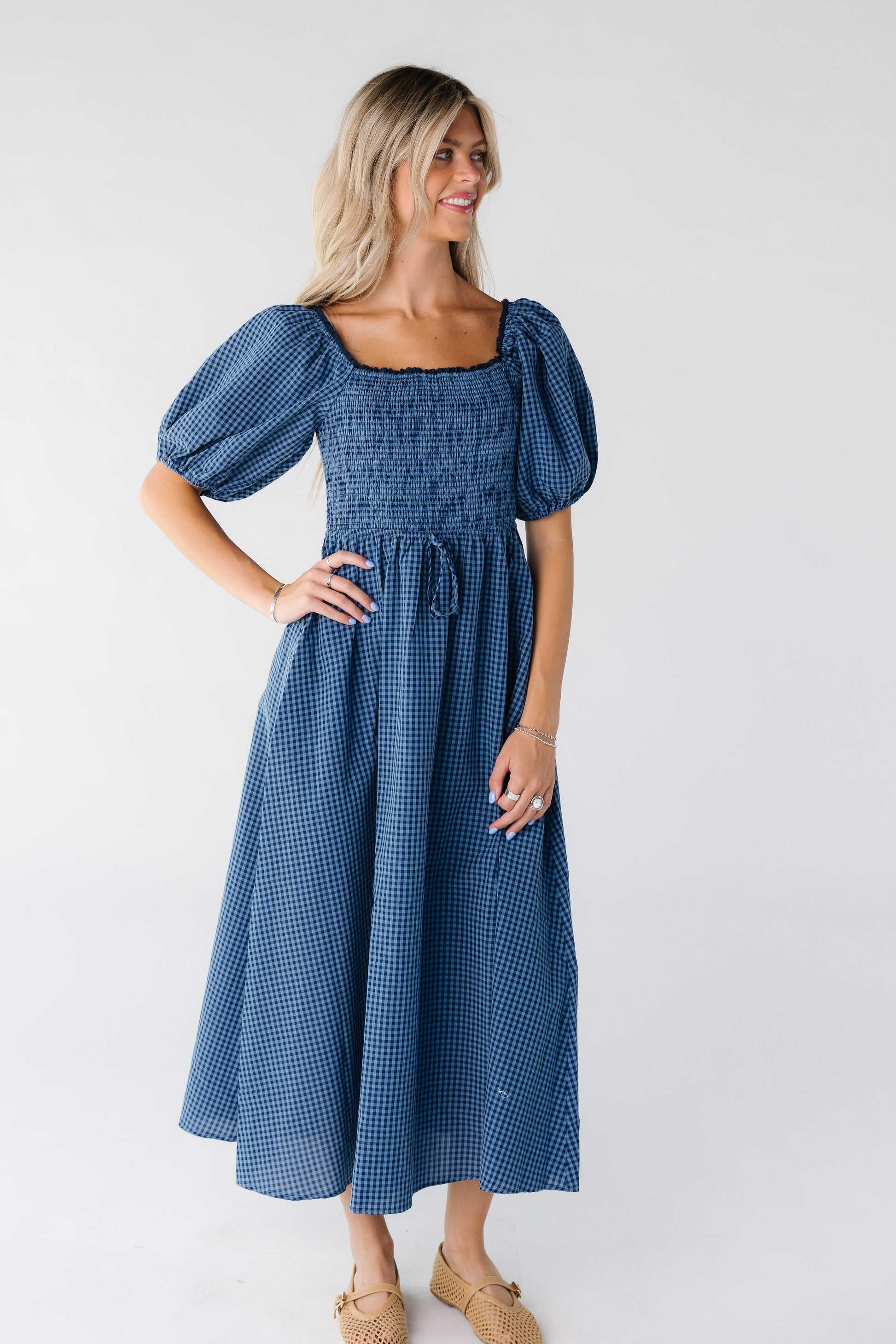 Woman wearing a blue gingham midi dress with large puff sleeves