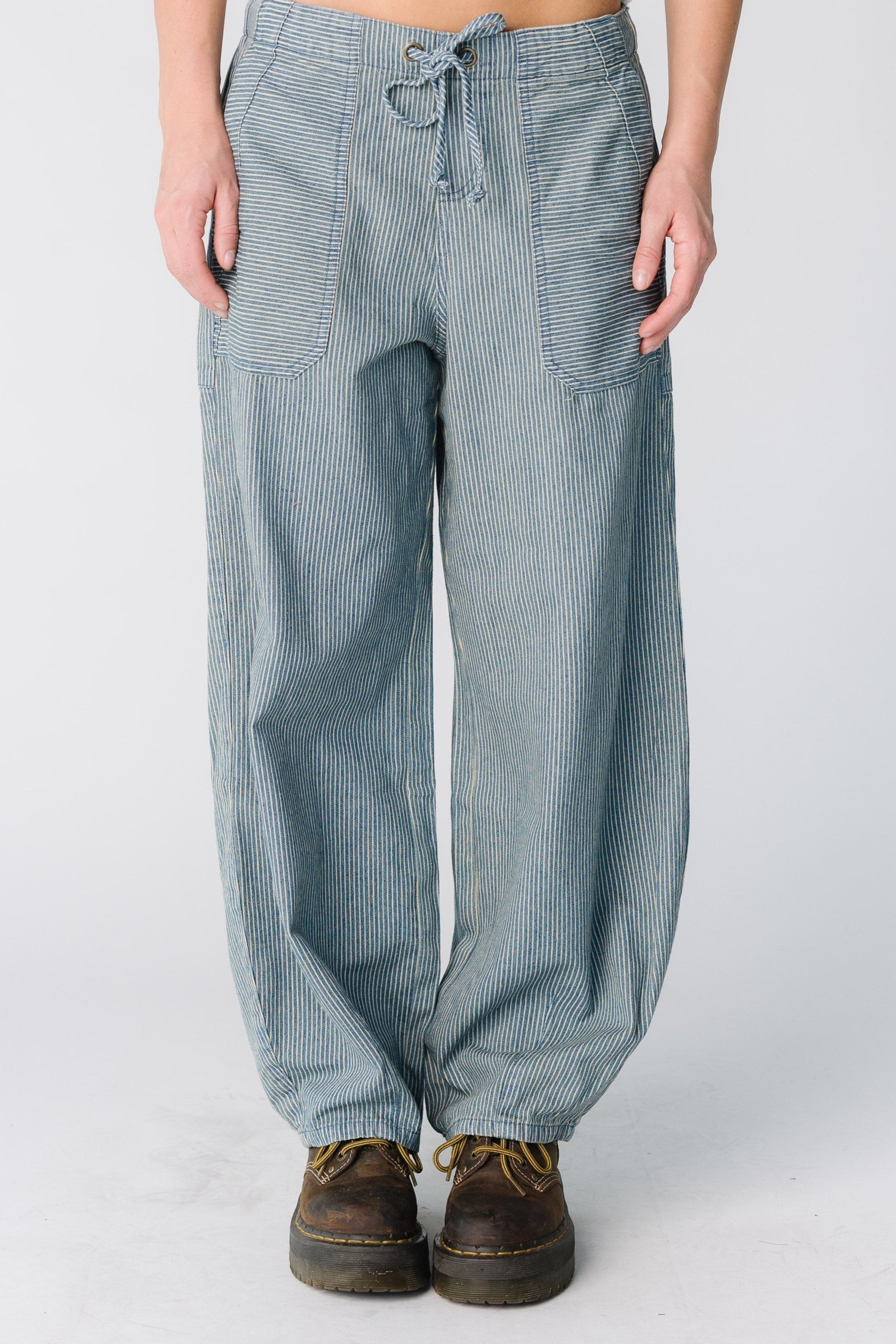 Woman wearing a pair of stripe denim barrel pants with large front pockets
