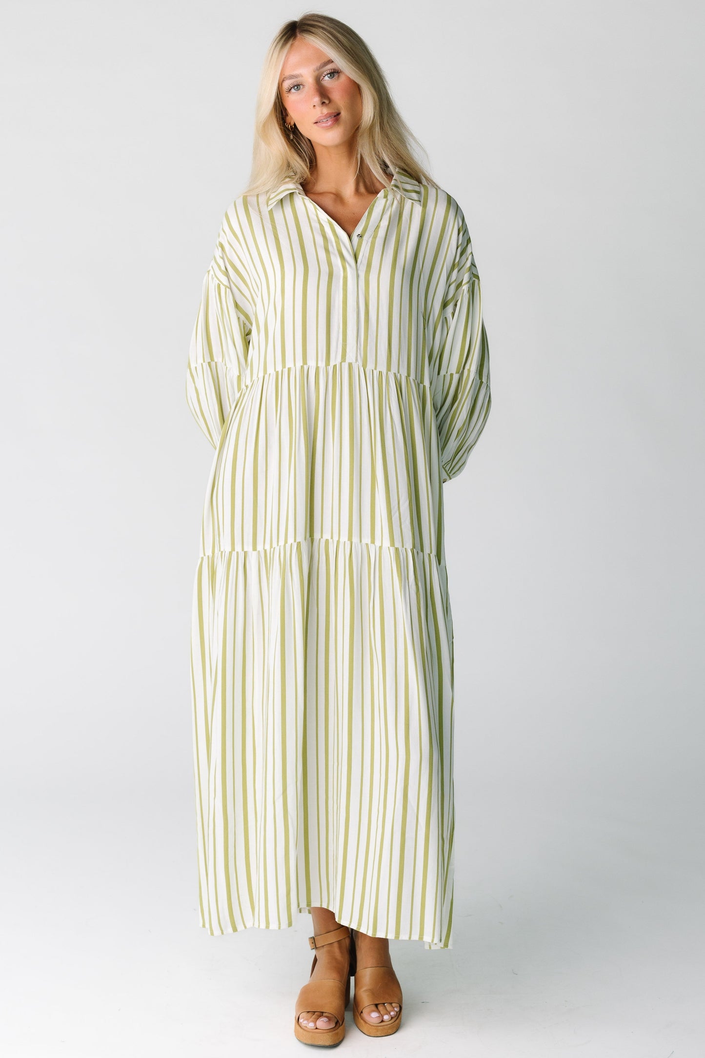 Woman woman wearing a green and white stripe midi dress with long sleeves and V-neckline