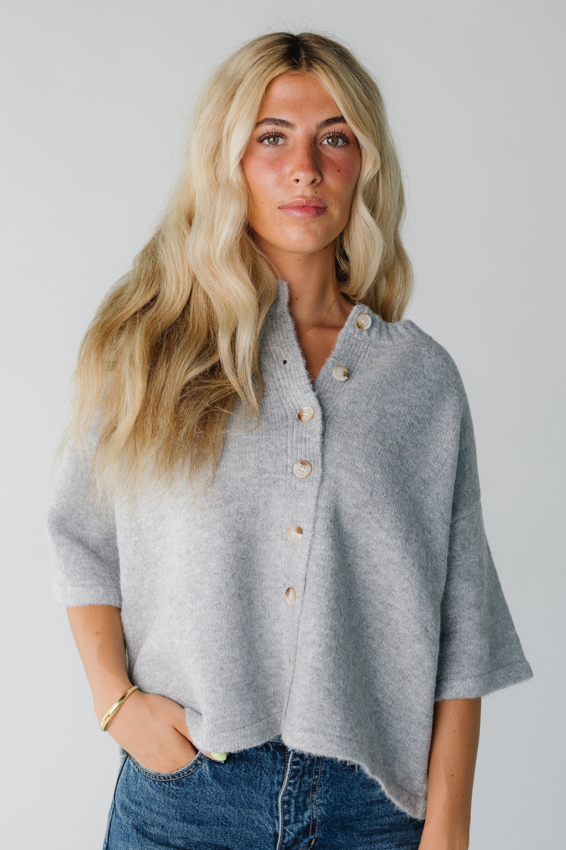 Woman wearing a grey button down cardigan with half length sleeves