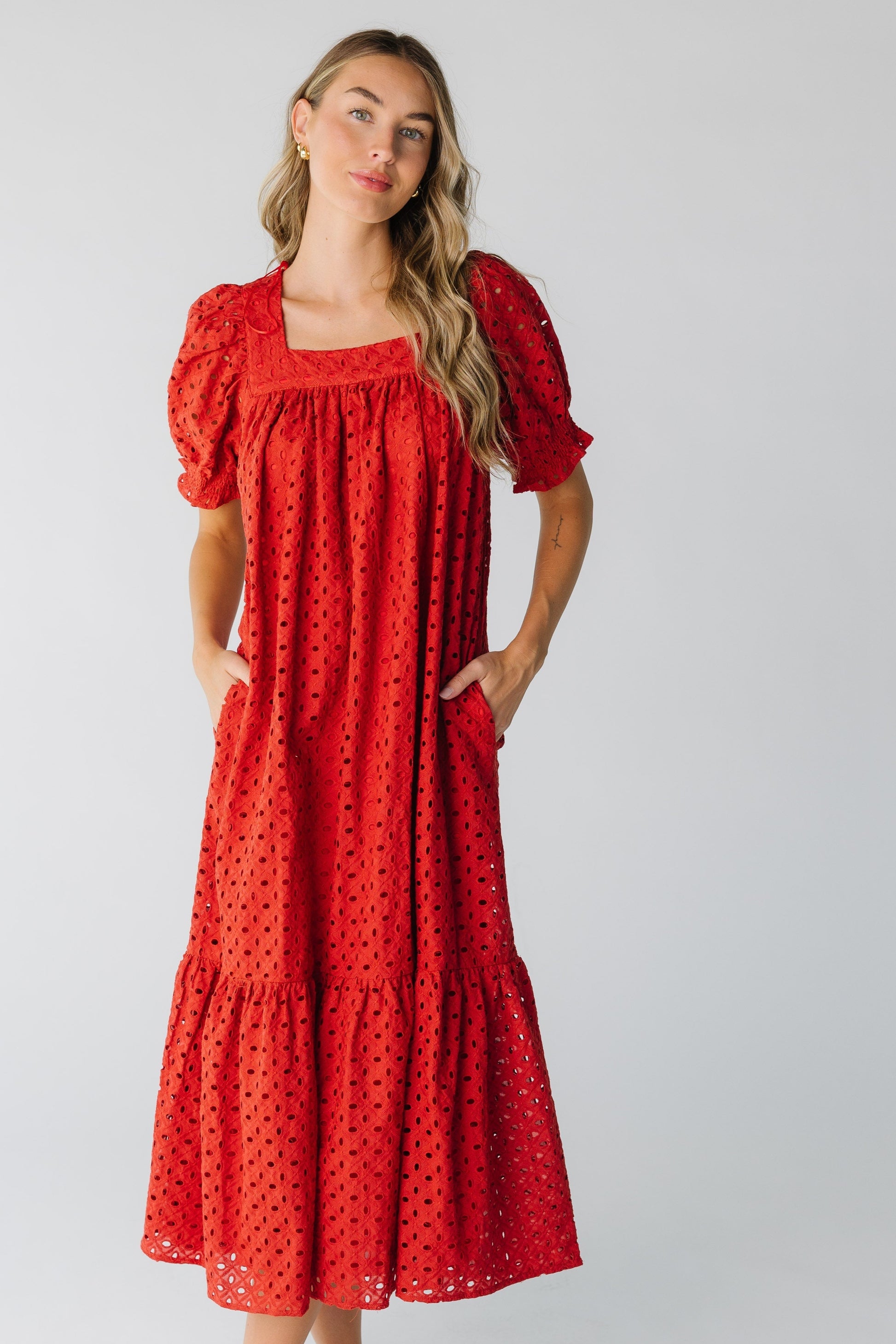 Woman wearing a red eyelet midi dress with wide pockets