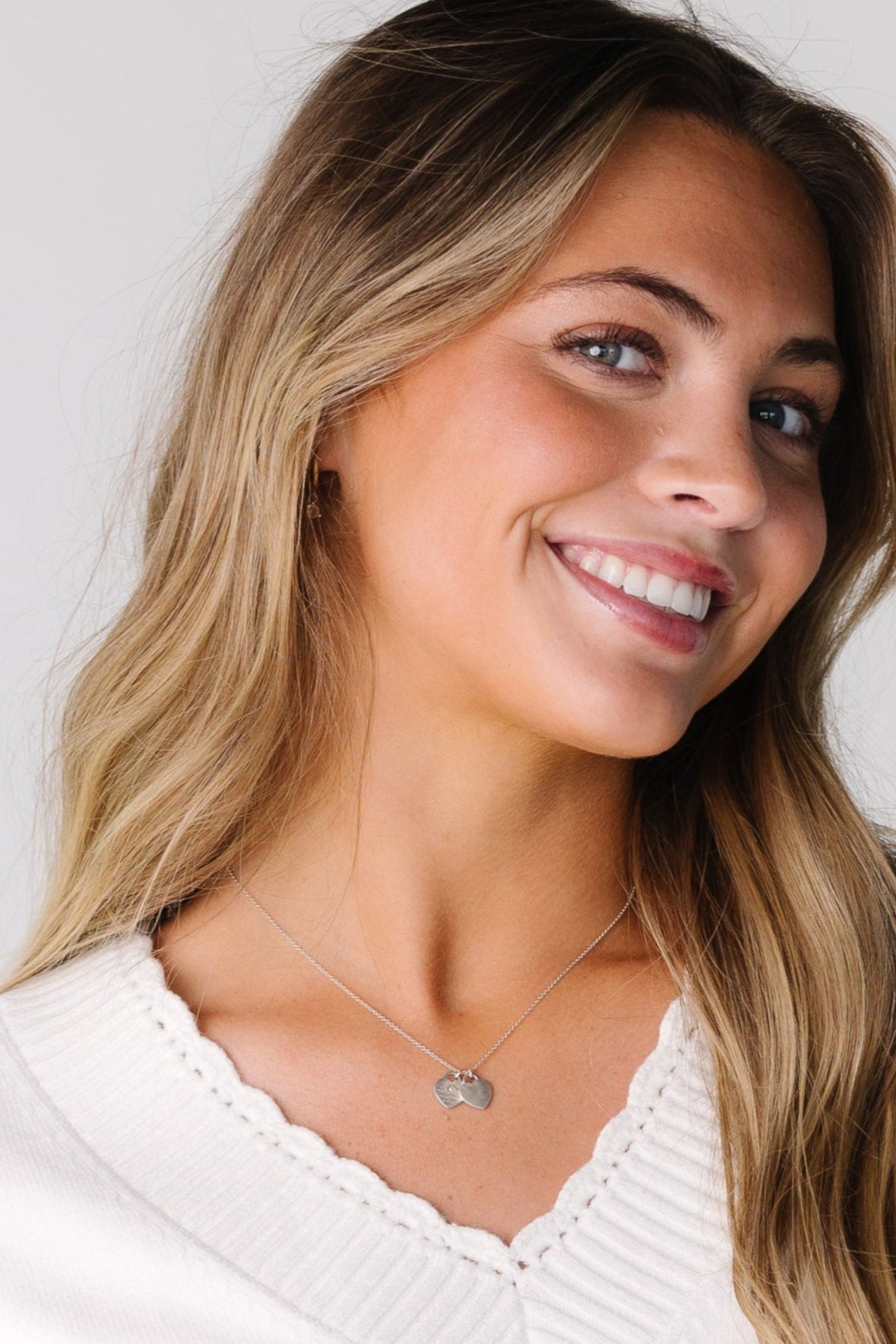 Close view of a woman wearing an off white sweater with a scallop edge.