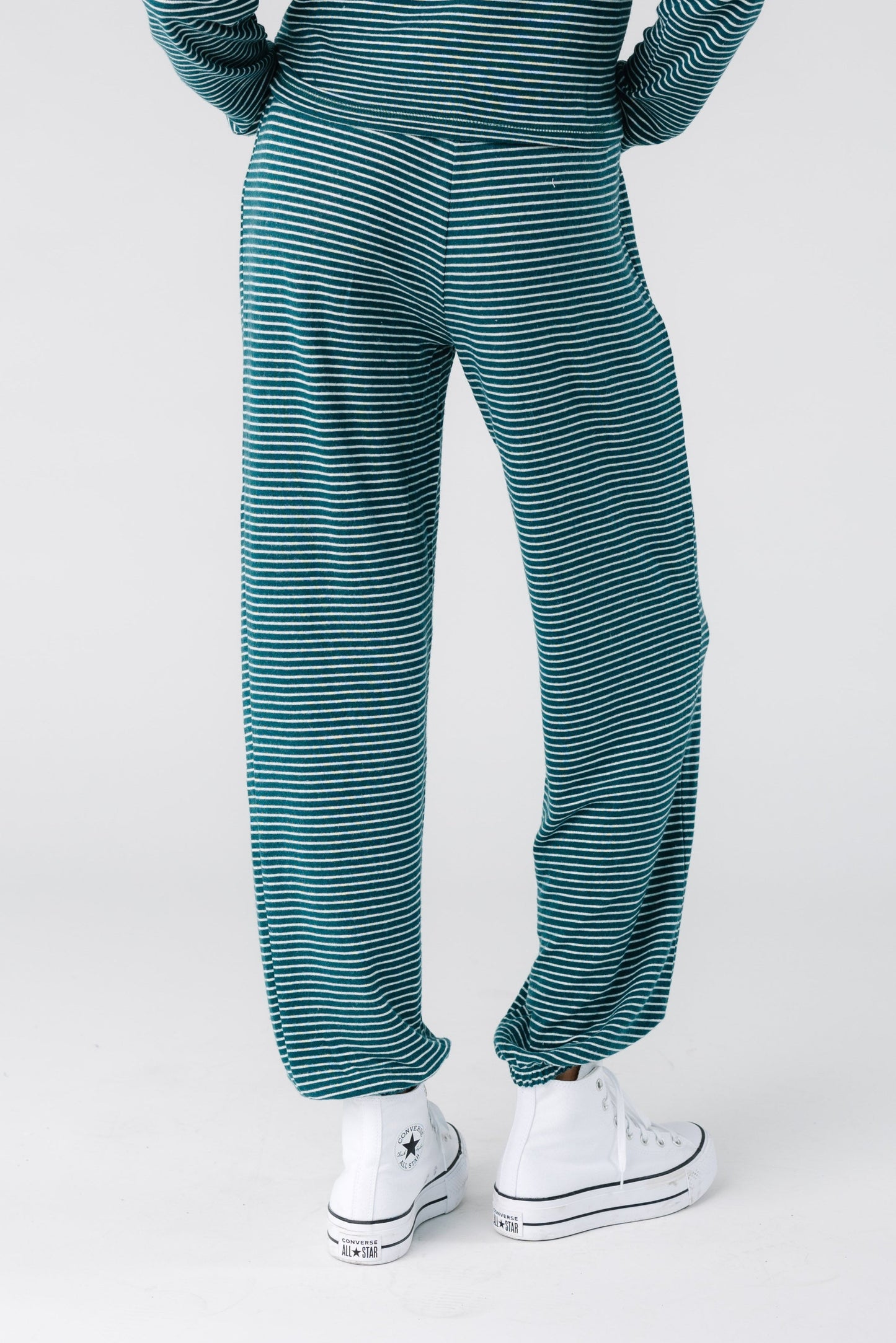 Back view of a woman wearing a pair of green and cream stripe lounge pants