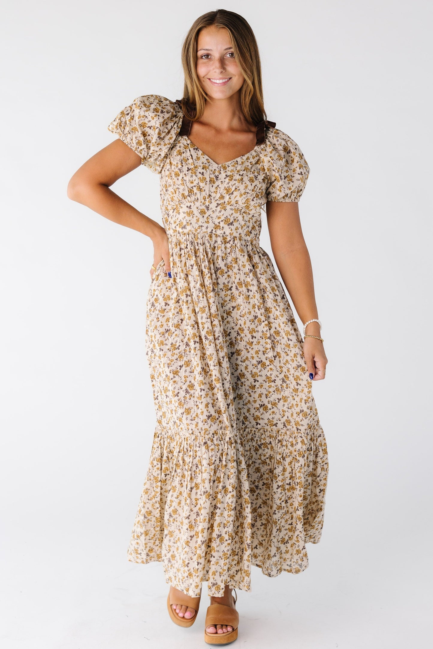 Woman wearing a gold floral midi dress with snug waistline and short sleeves