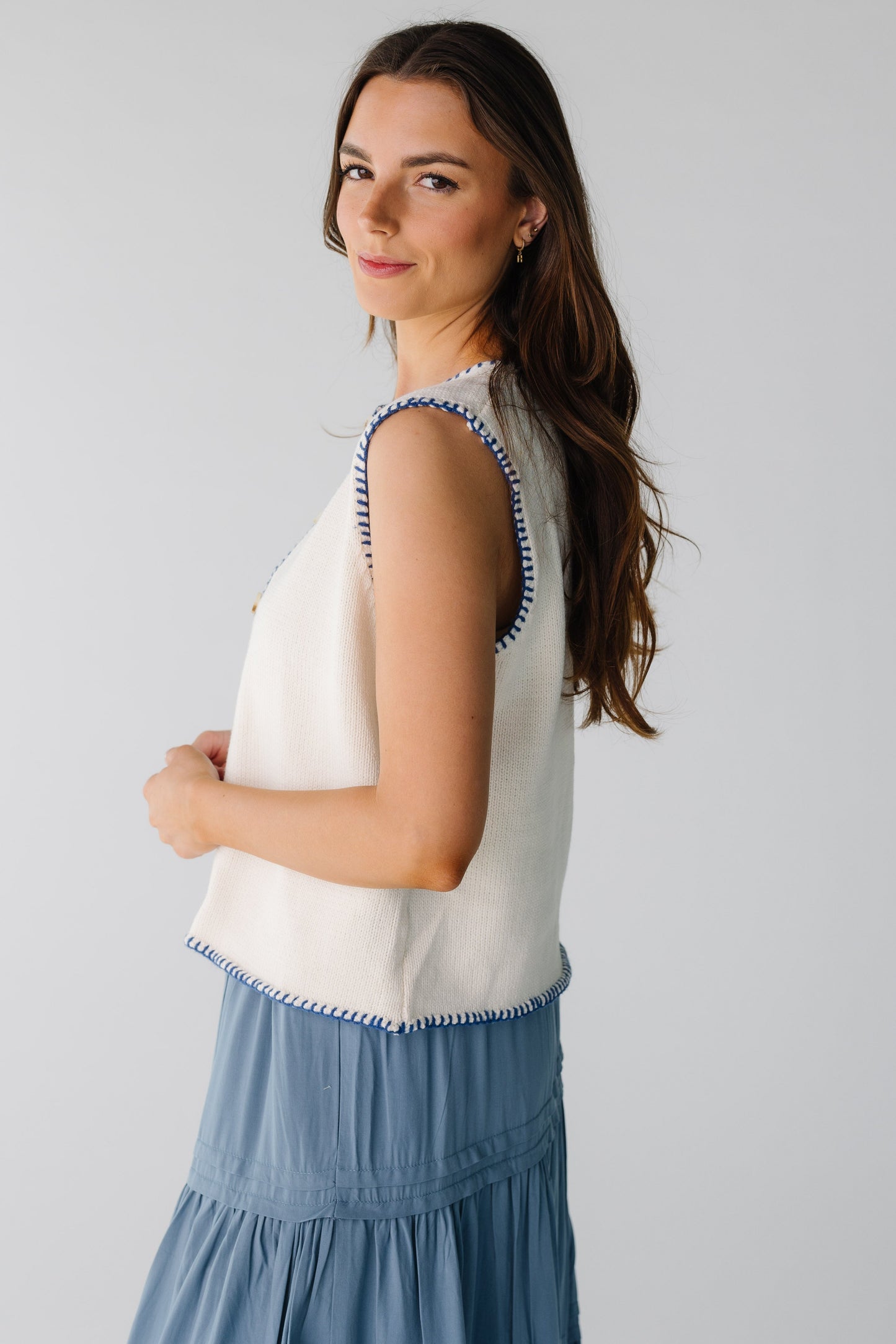 Side view of white sweater vest with navy stitch details
