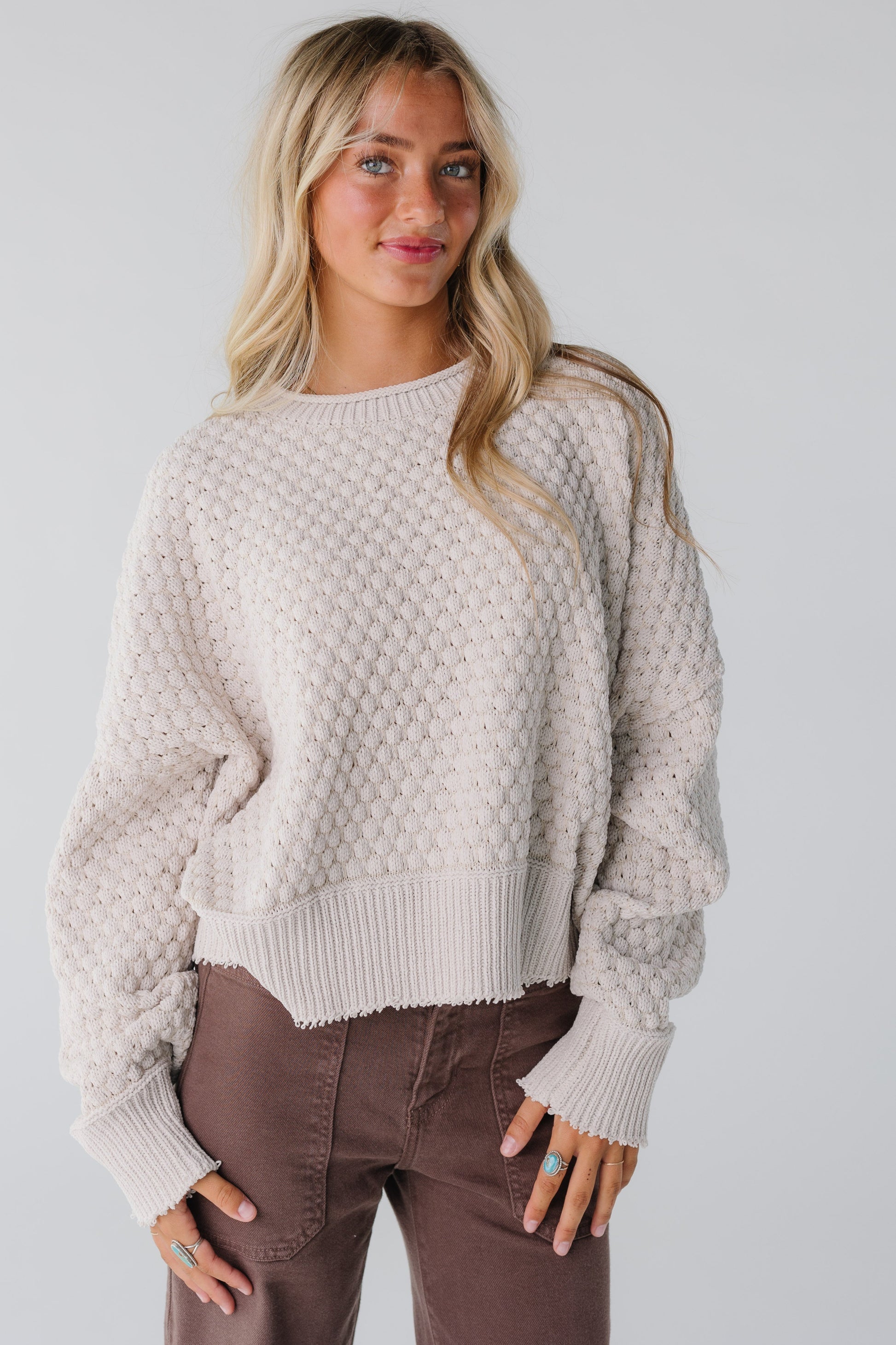 A woman wearing a textured knit sweater in natural with long sleeves