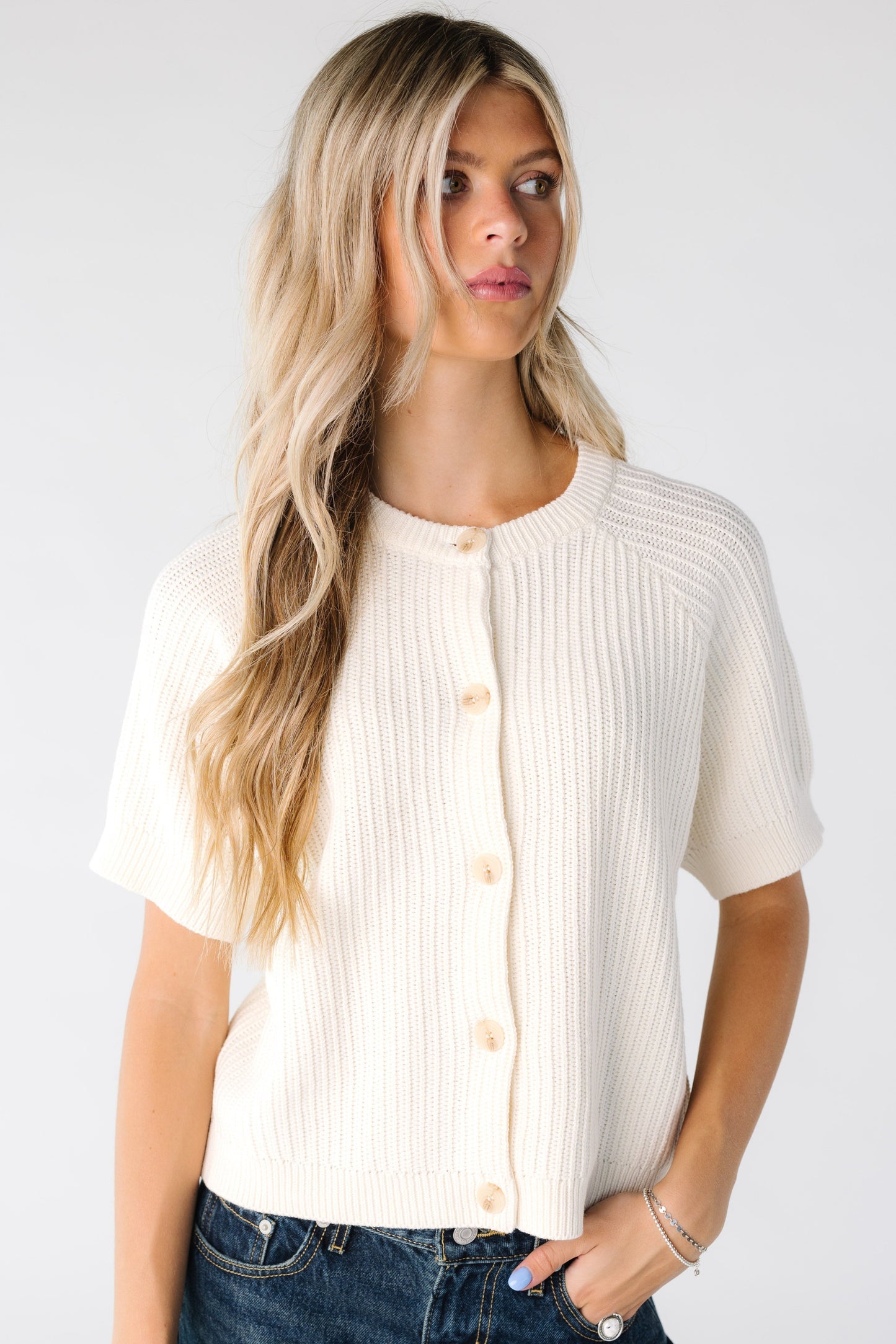 Woman wearing an ivory cardigan with textured stripes and short sleeves