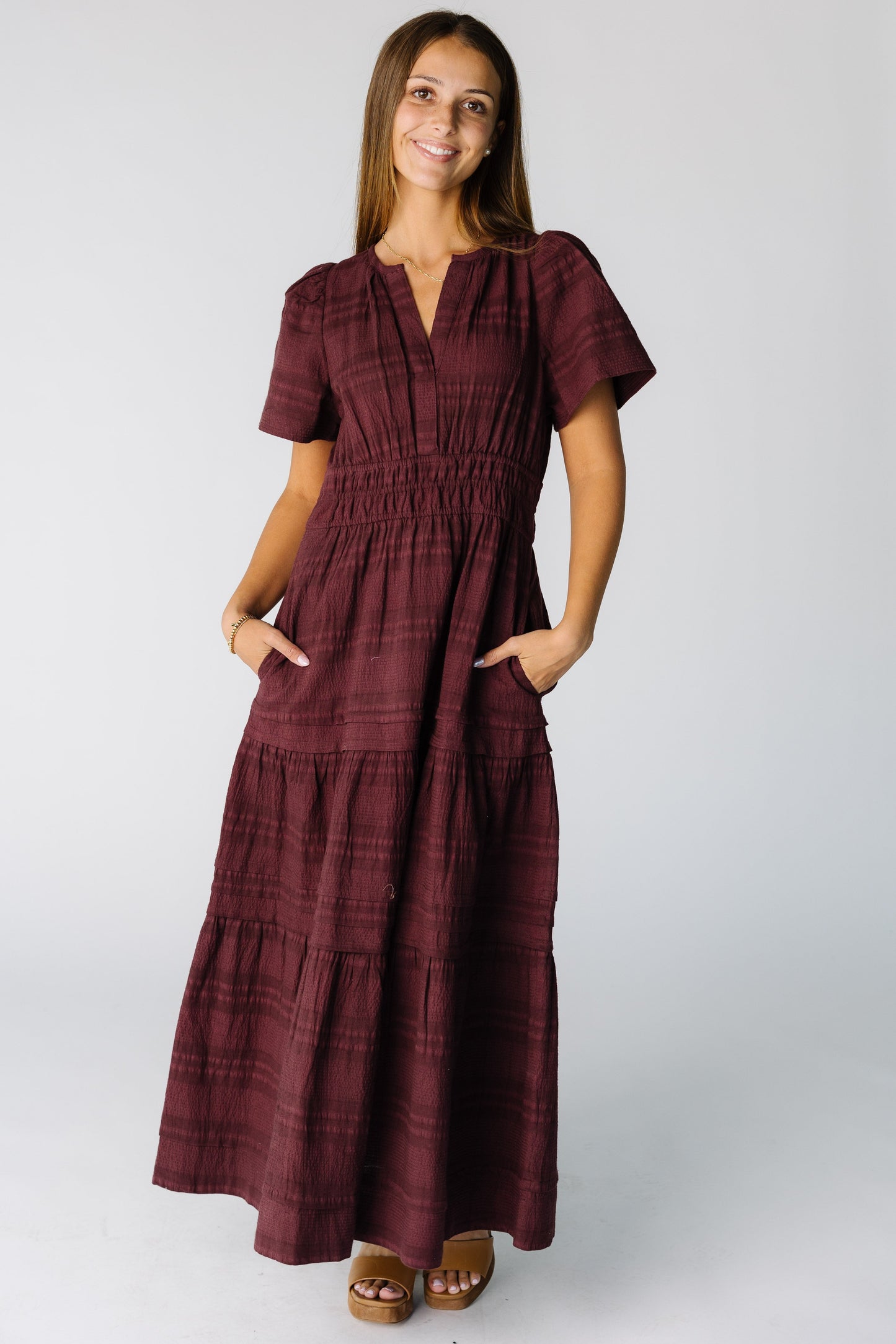 Woman wearing a modest burgundy maxi dress with side pockets and V-neckline