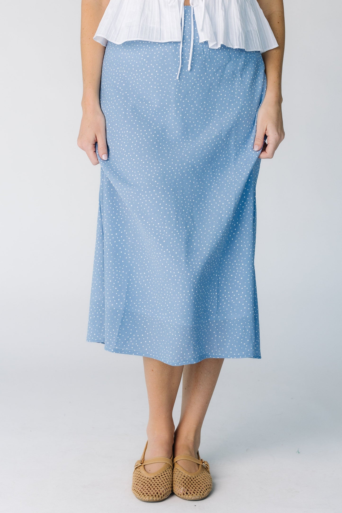 Woman wearing a modest A-line midi skirt in a light blue polka dot.