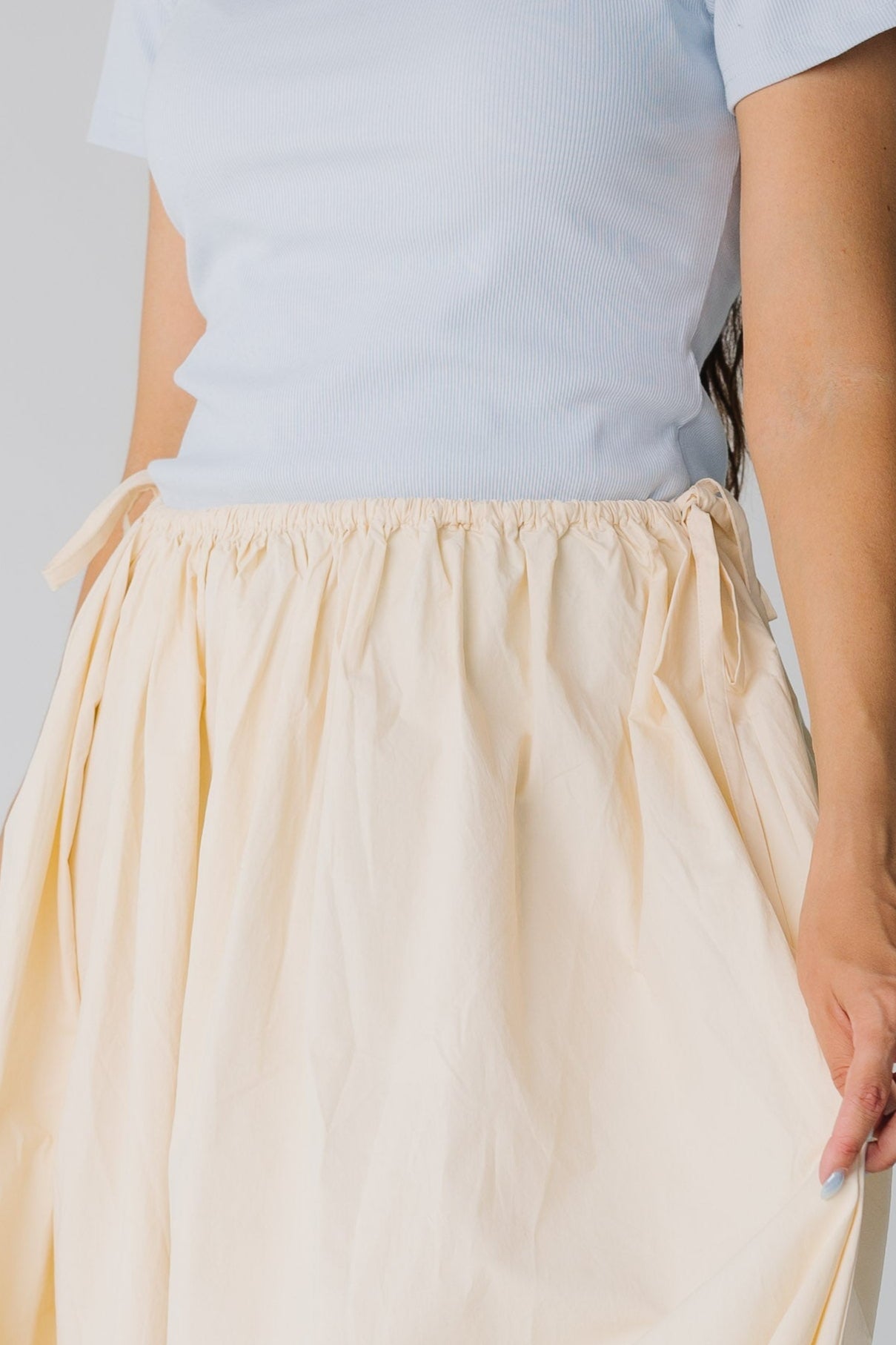 Close view of waist details on cream midi skirt