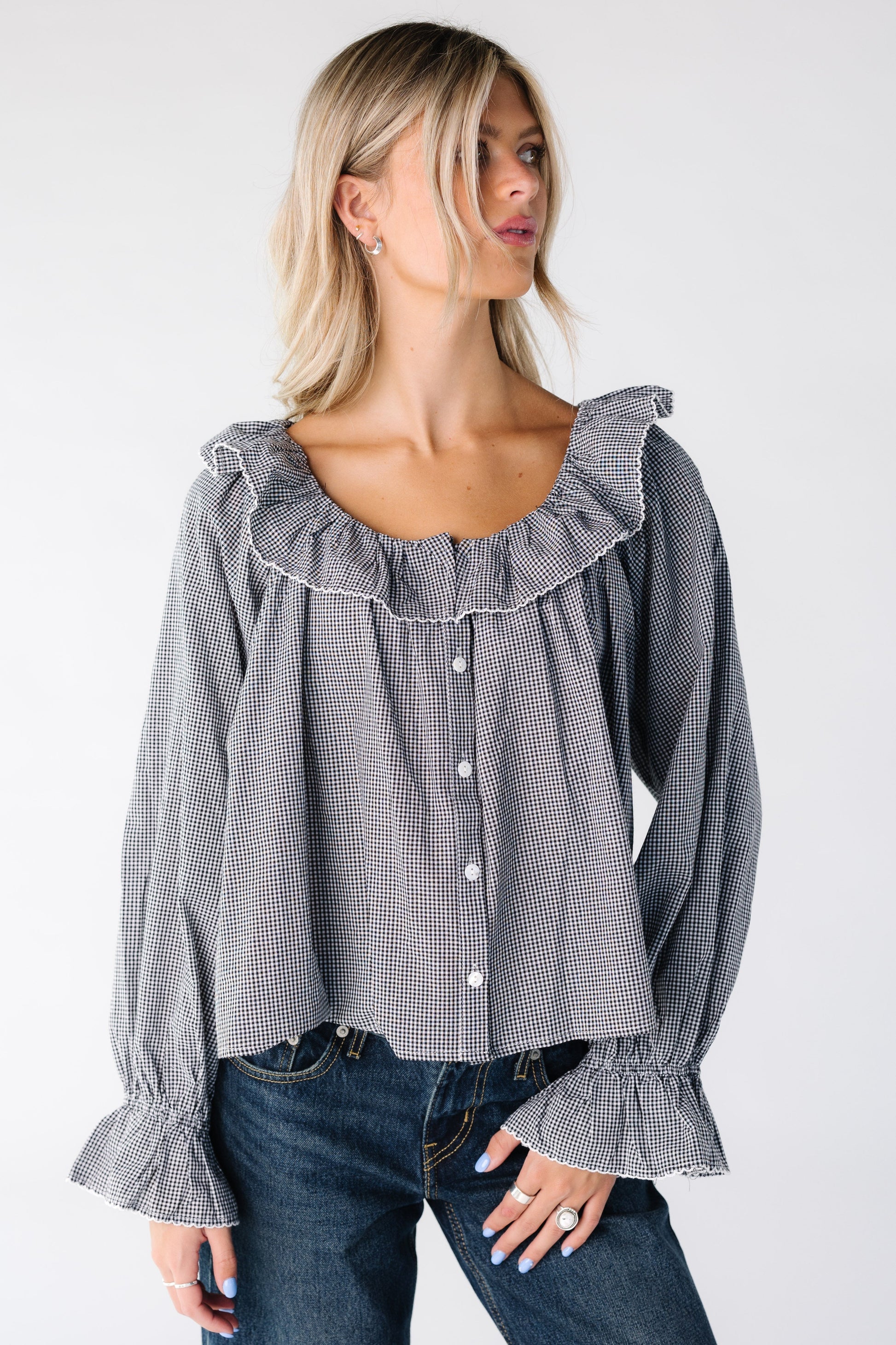 Woman wearing a black gingham loose fitting top with a ruffle collar