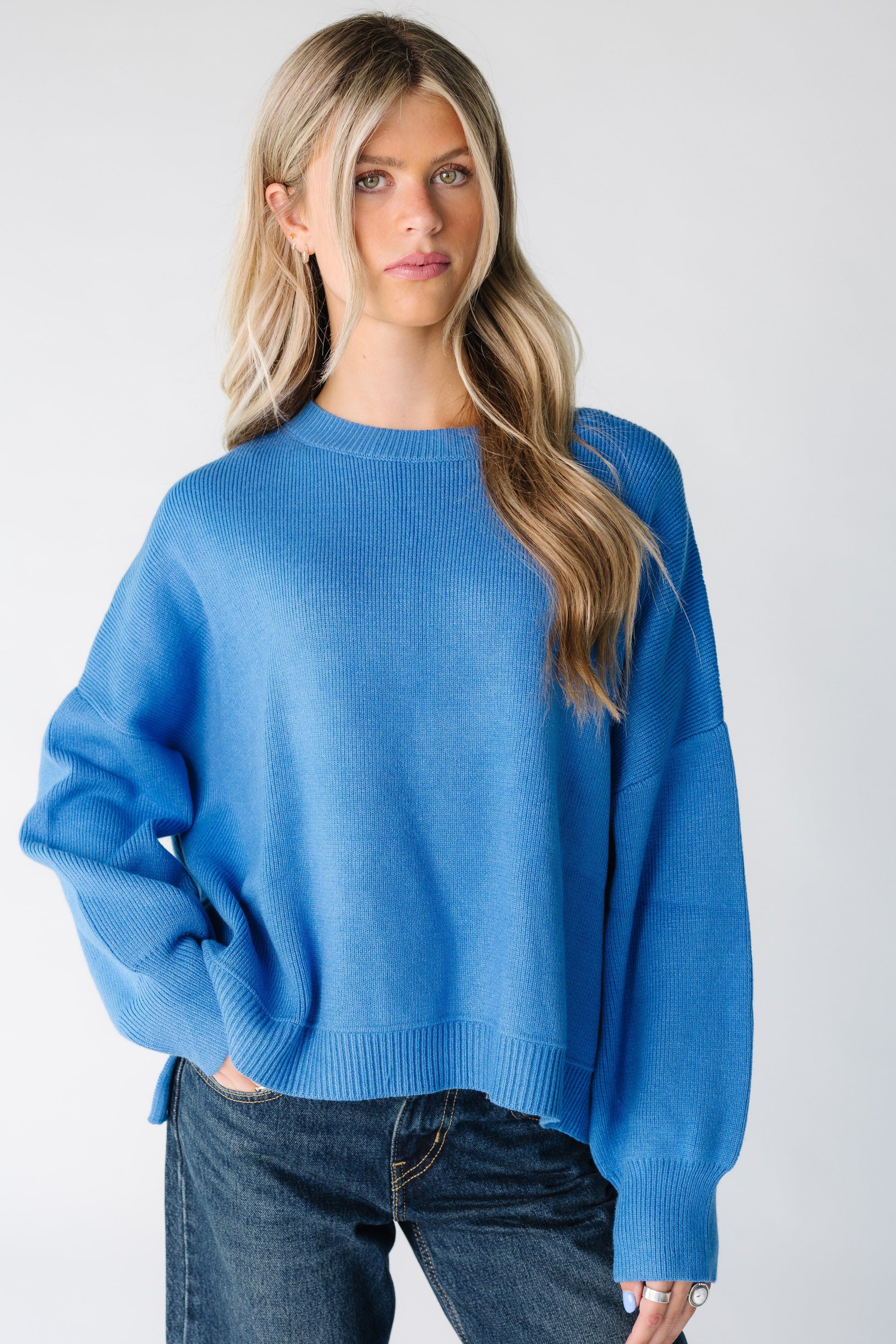 Woman wearing a blue loose fitting sweater with long sweater