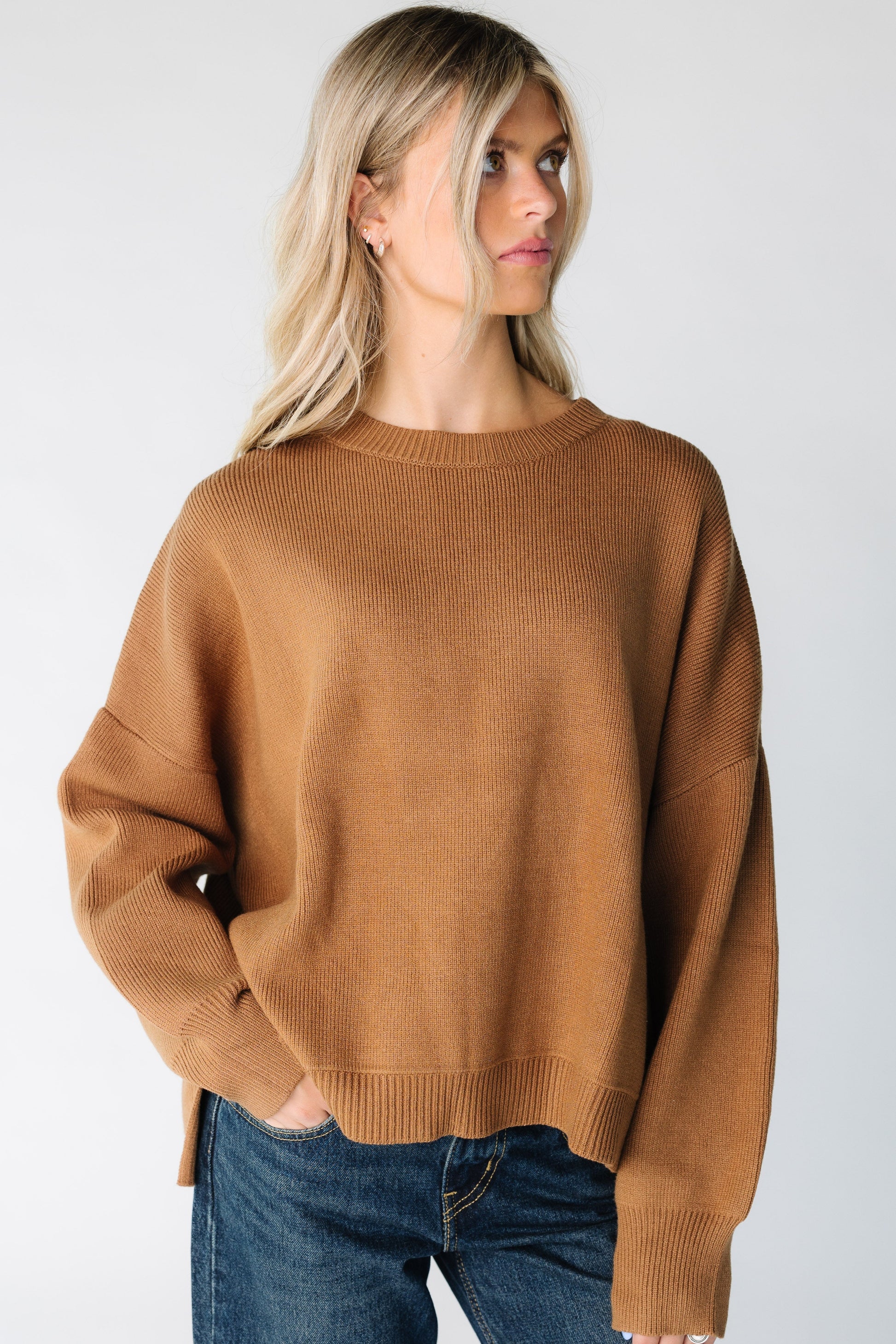 Woman wearing a brown sweater with drop shoulders and long sleeves