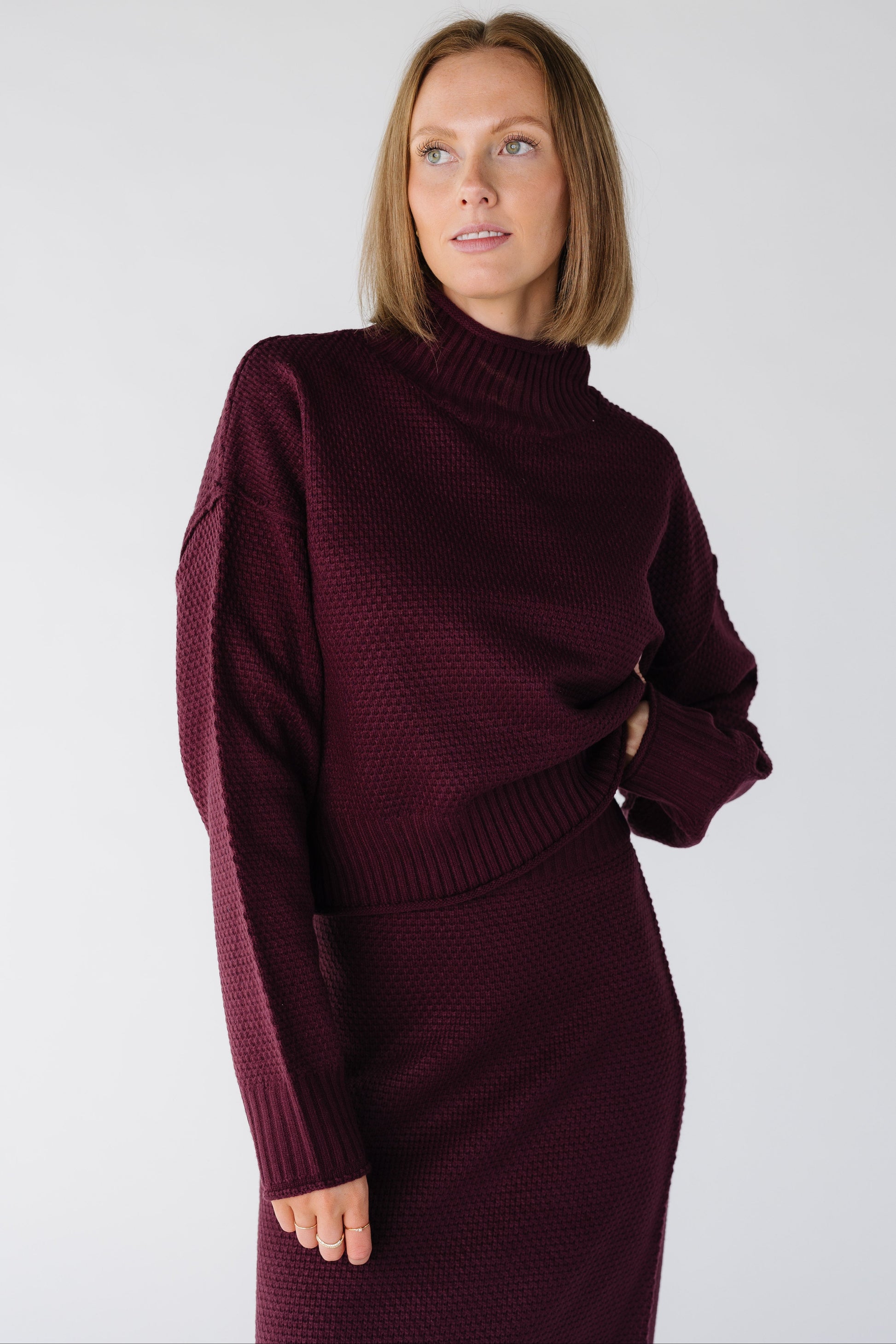 Close view of a woman wearing a dark cherry textured sweater and skirt set