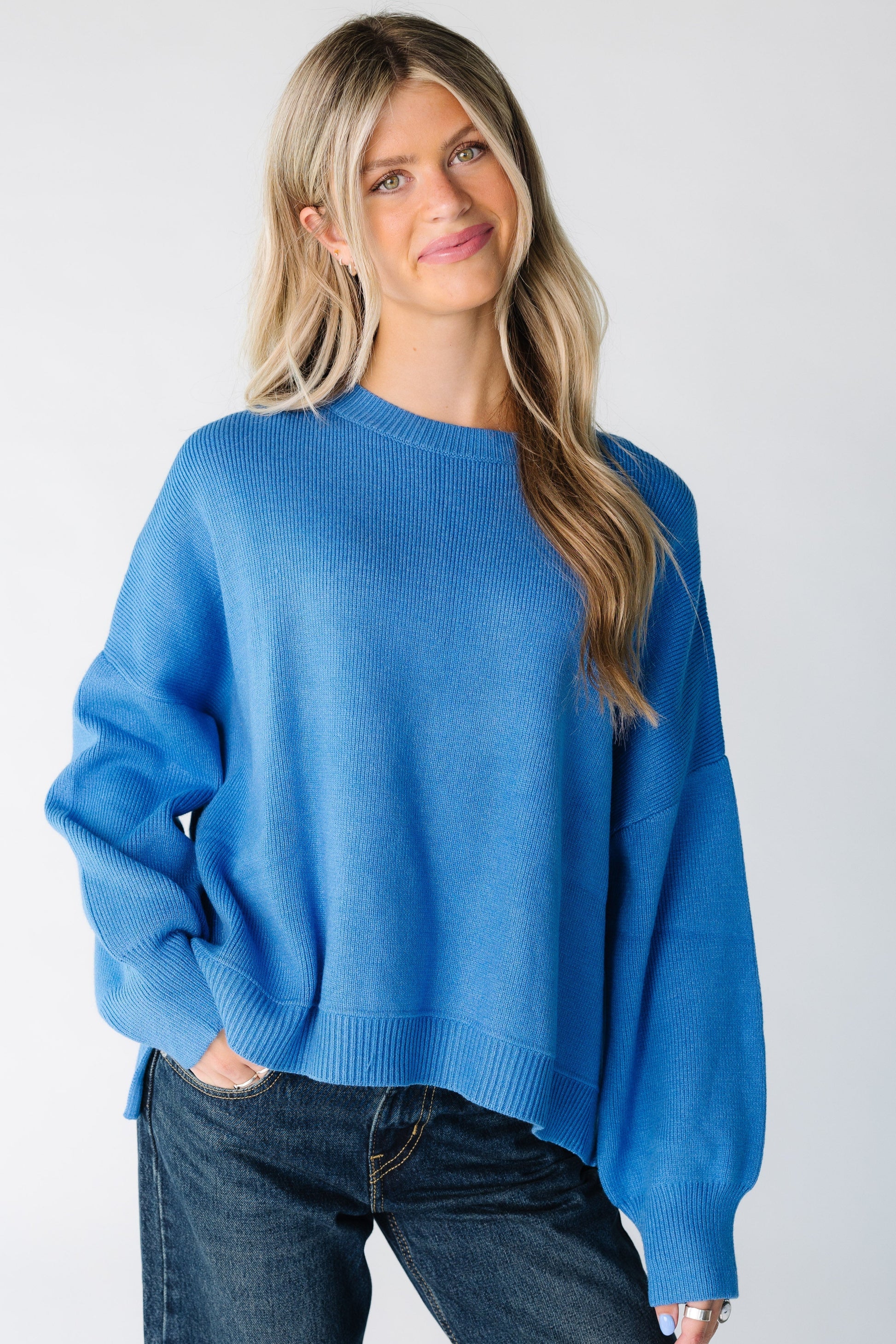 Woman wearing a loose fitting blue pullover sweater with long sleeves