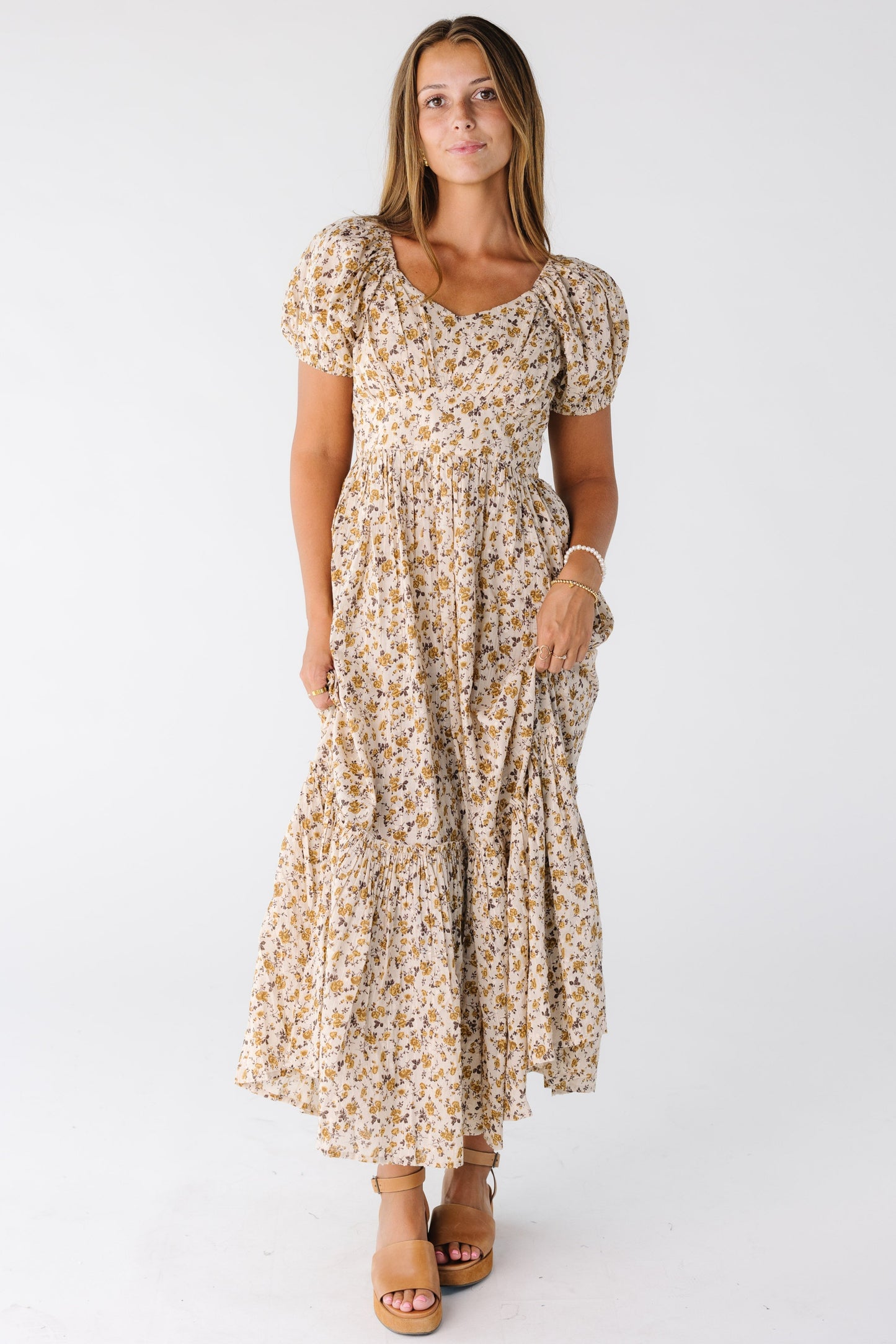 Woman wearing a gold floral dress with short sleeves