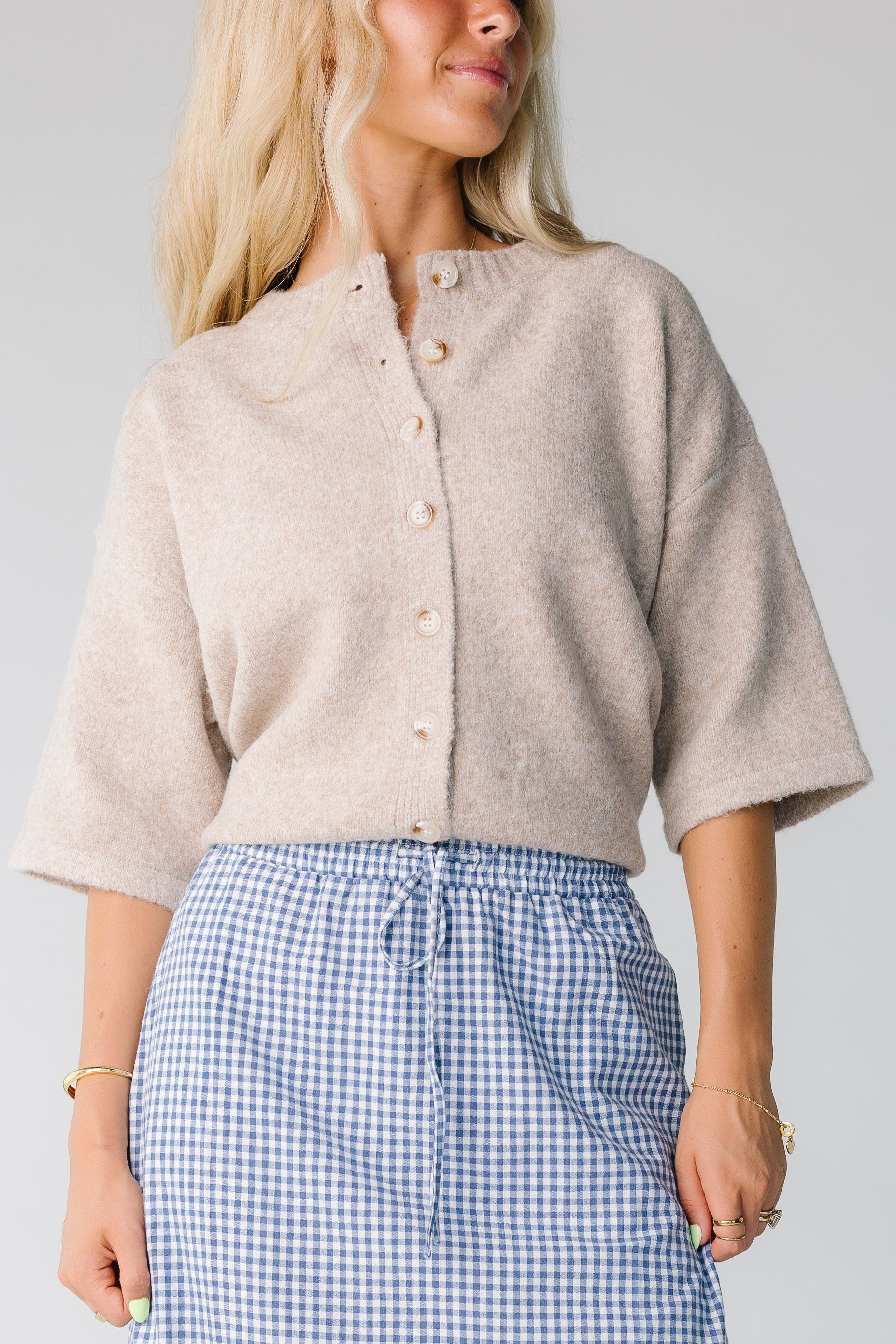 Woman wearing a mocha tan button down cardigan with half length sleeves