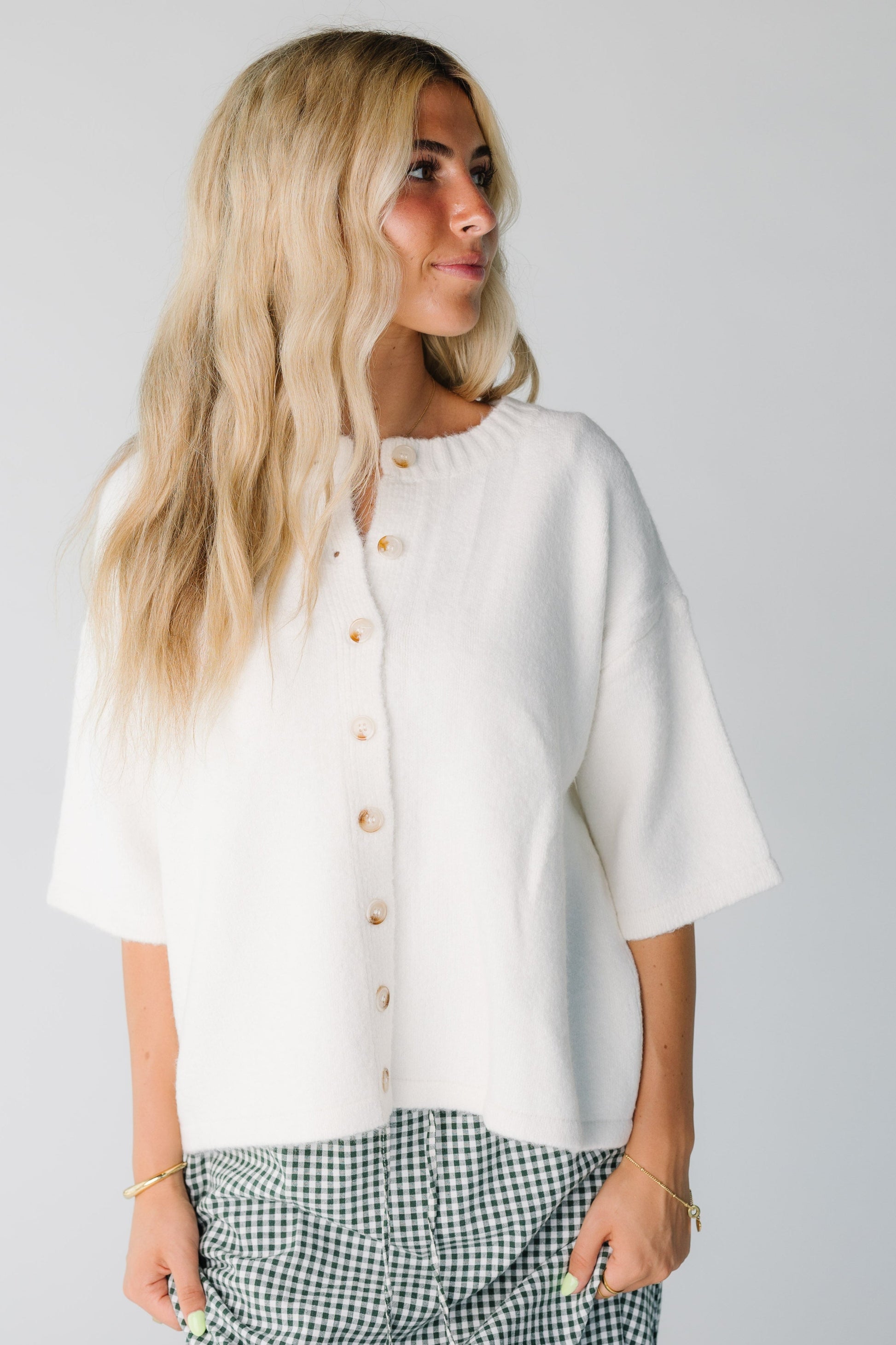 Women wearing an off white button down cardigan with half length sleeves