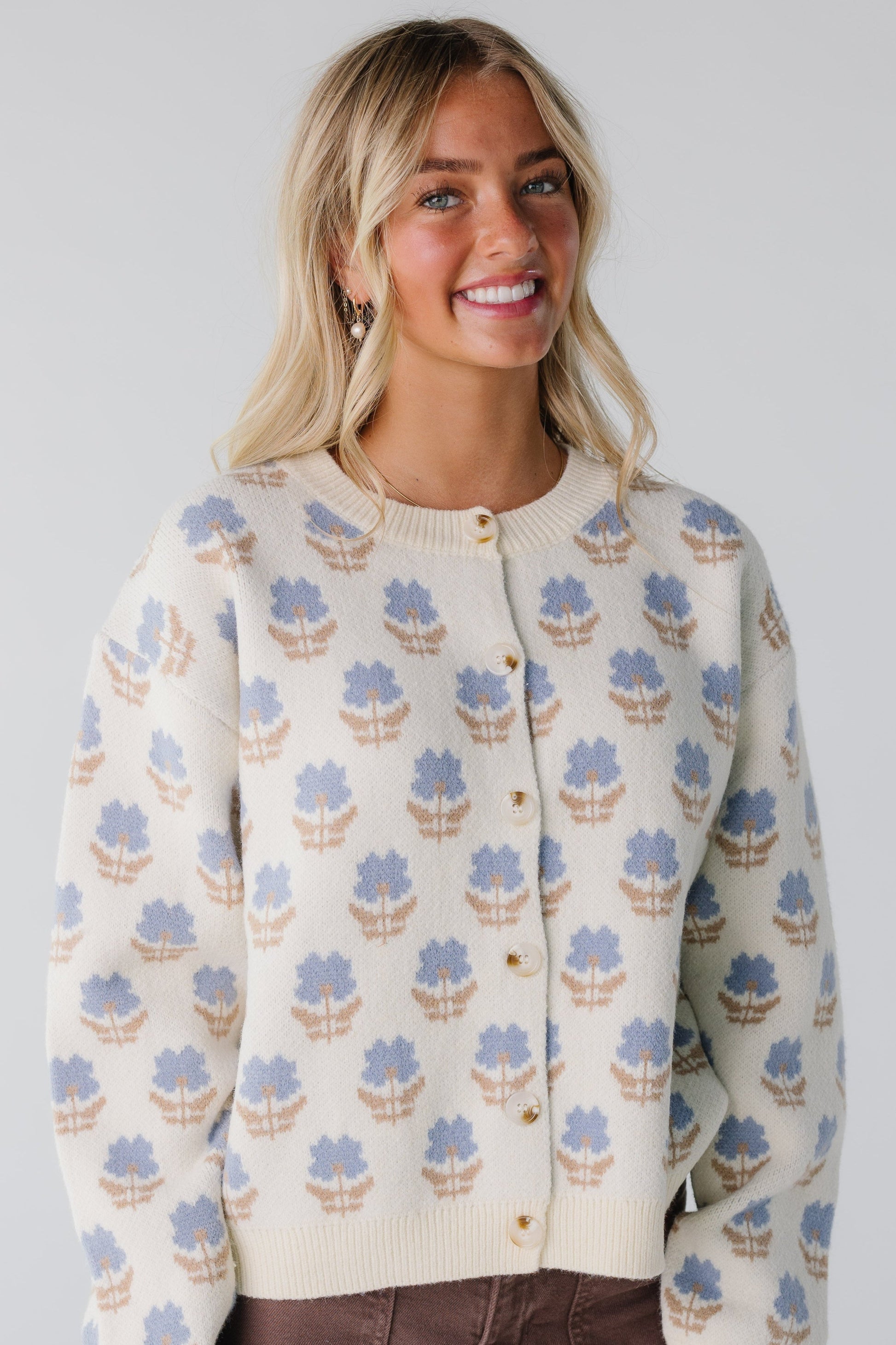 Woman wearing a cream and blue floral button down cardigan
