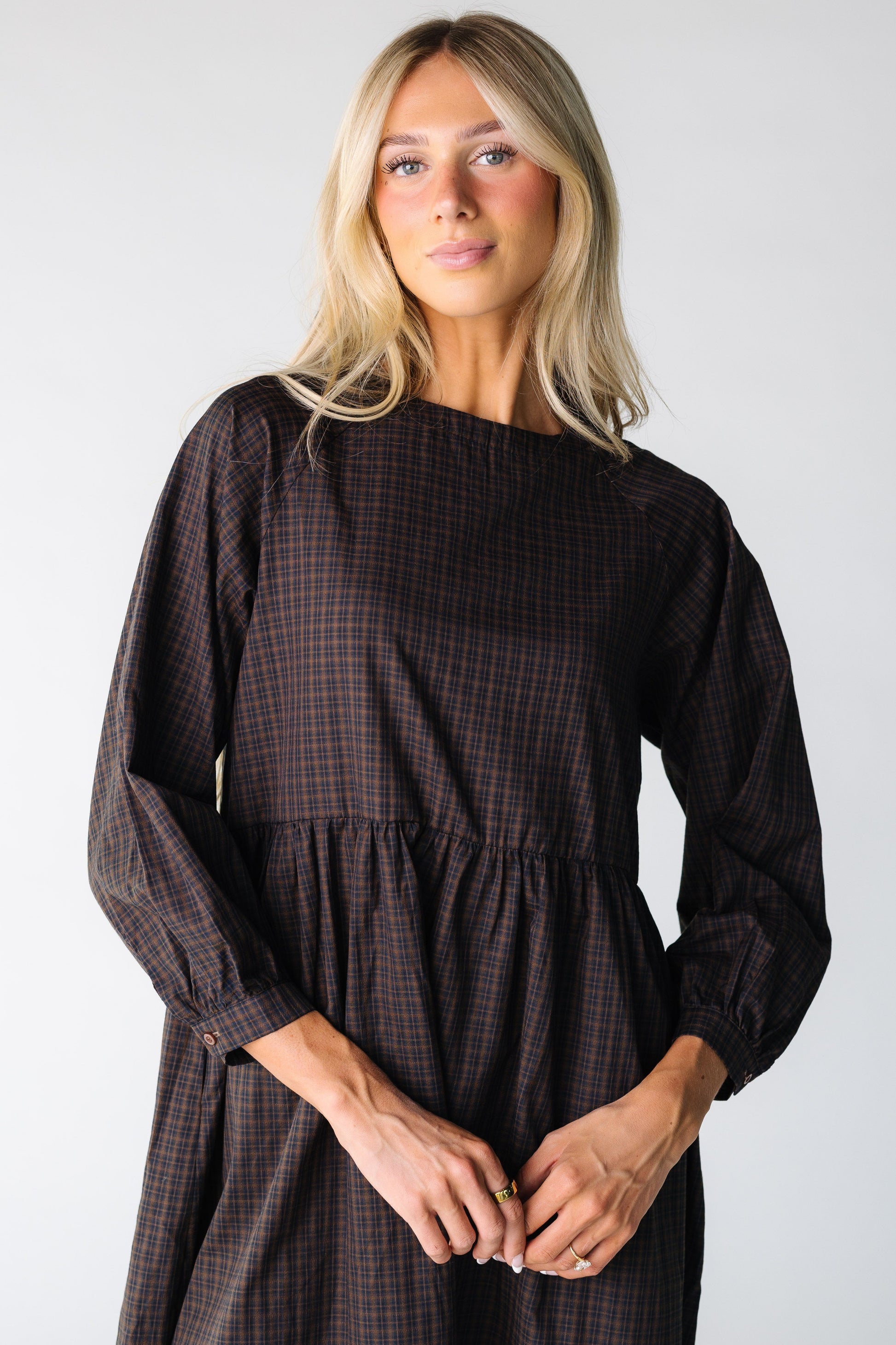 Close view of a woman wearing a brown plaid dress with long sleeves