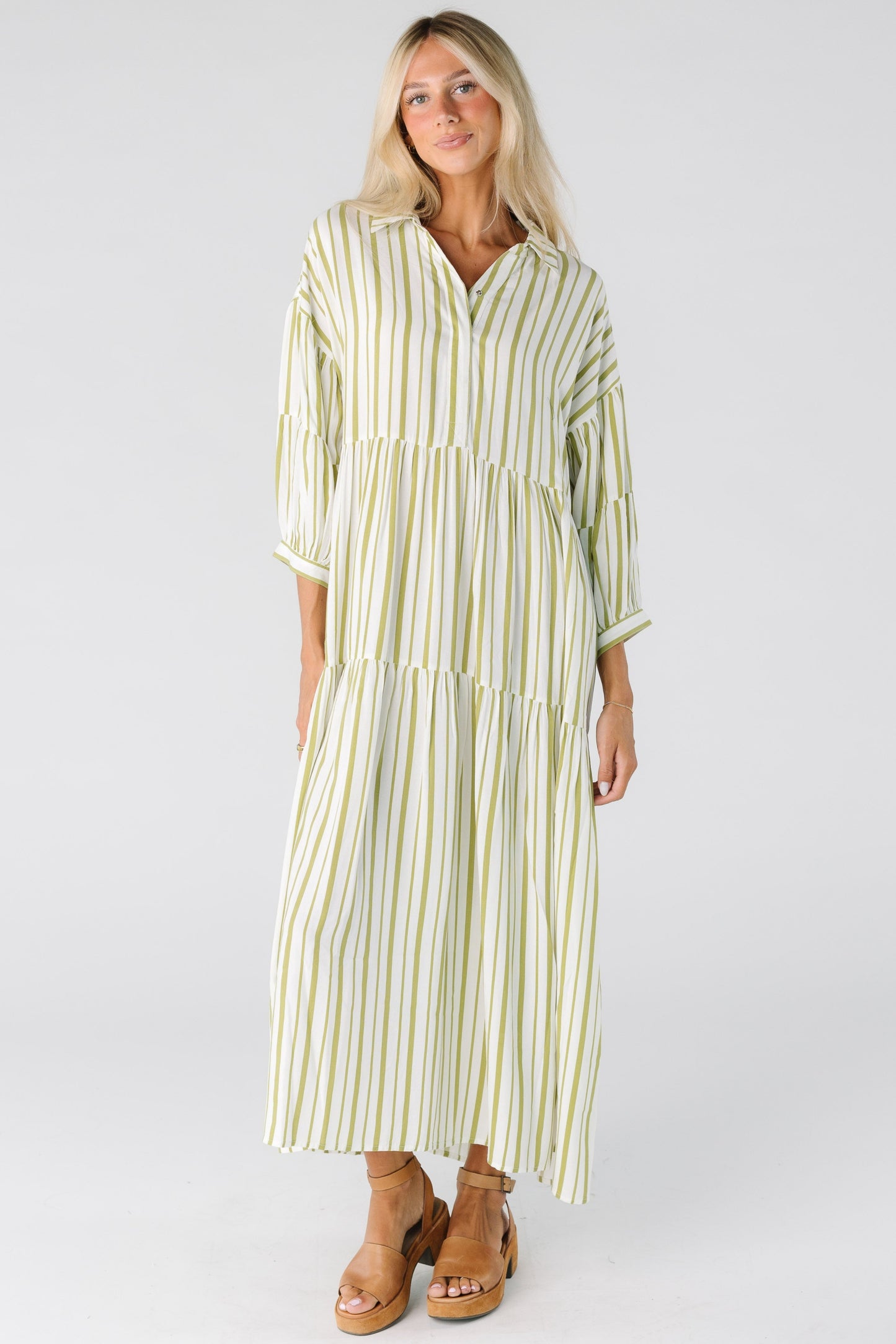 Woman in an ivory and green stripe loose fitting dress with long sleeves