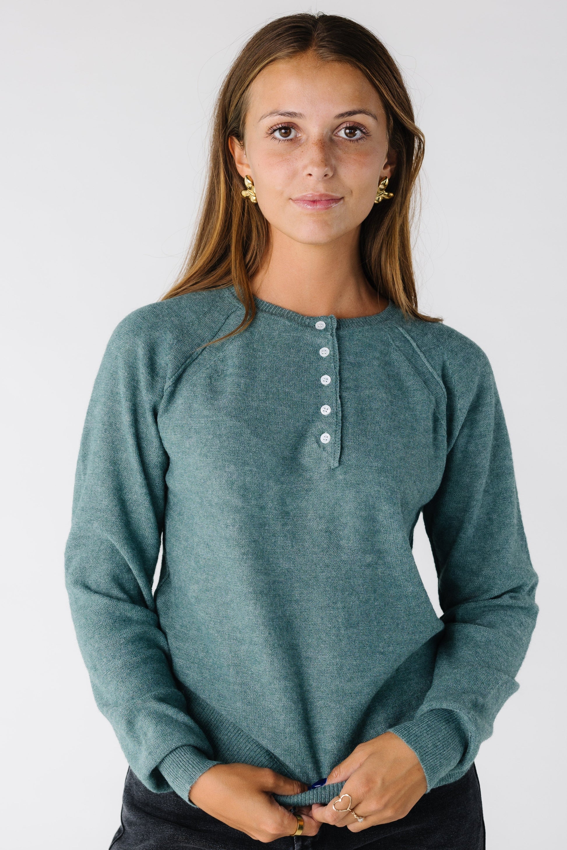 Woman wearing a teal Henley top with raglan sleeves and long sleeves