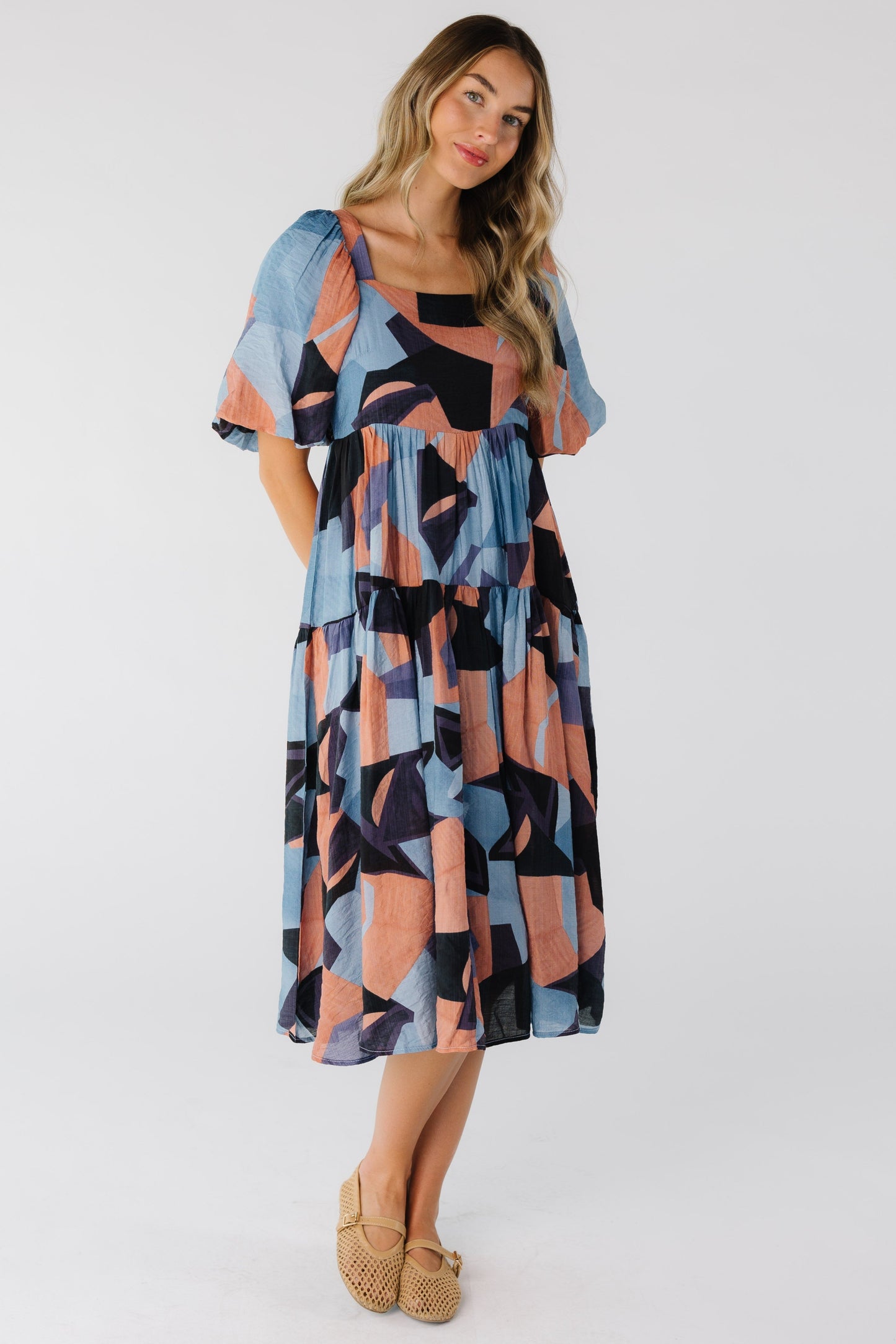 Woman wearing a multi color below knee dress with square neckline