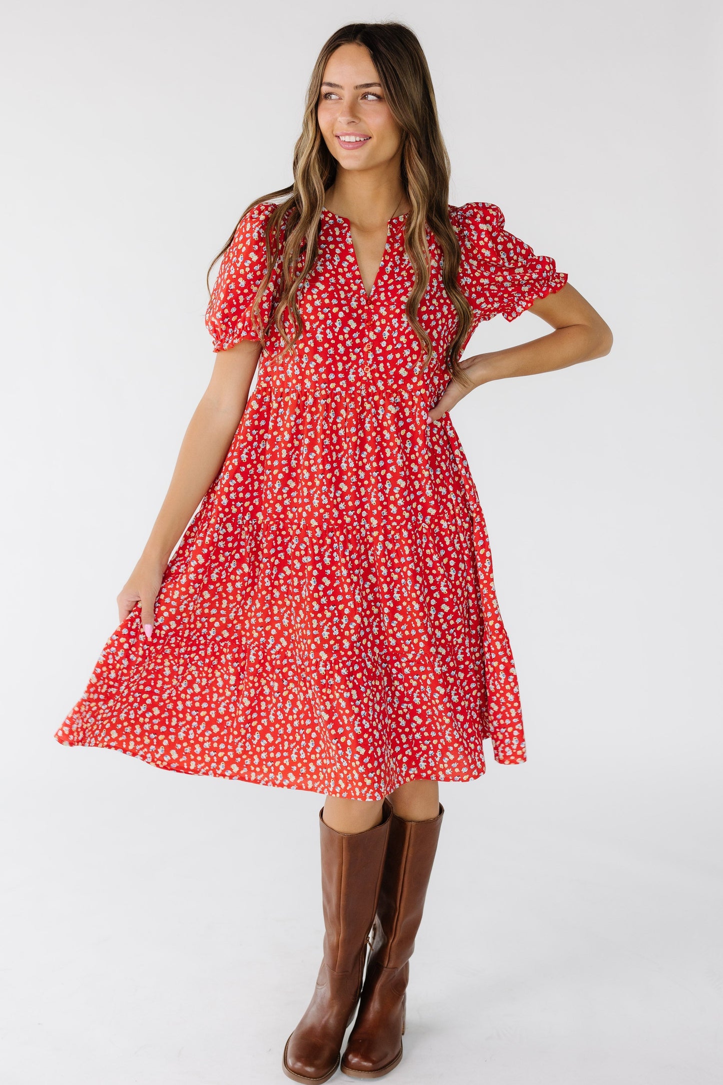 Woman wearing a modest red floral, knee length dress that is loose fitting and a V-neckline.