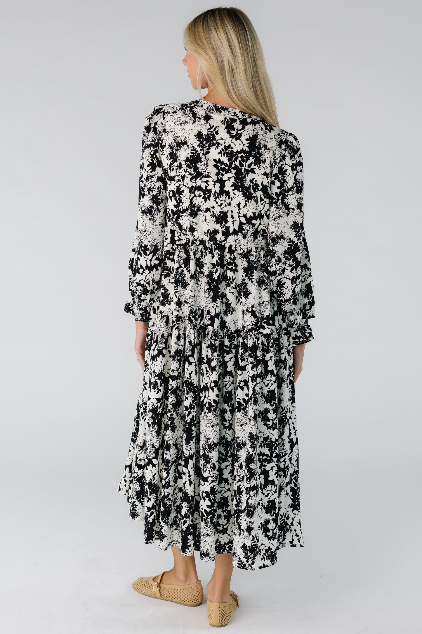 Back view of a woman wearing a loose fitting midi dress in black and white floral print