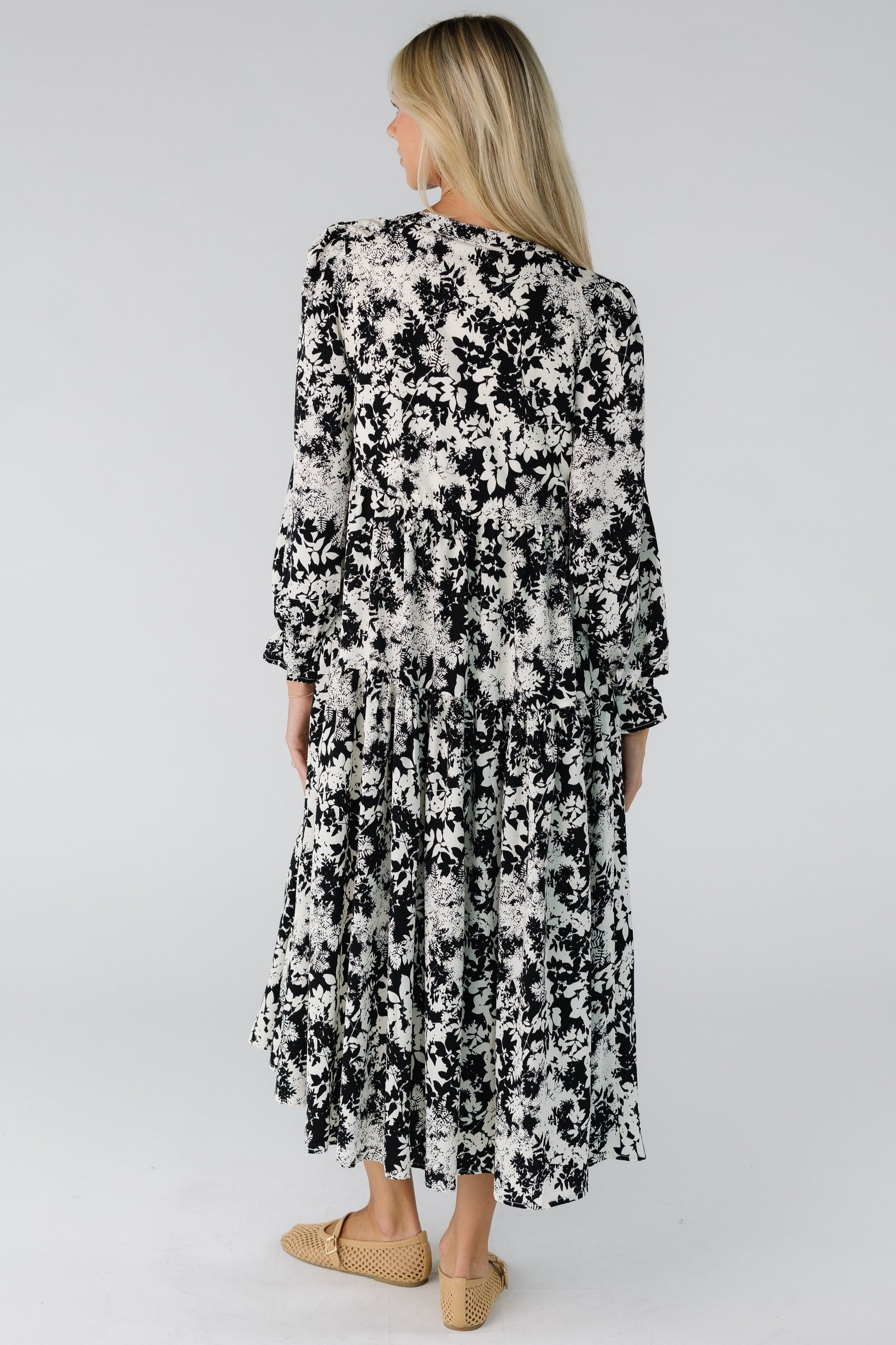 Back view of a woman wearing a loose fitting midi dress in black and white floral print