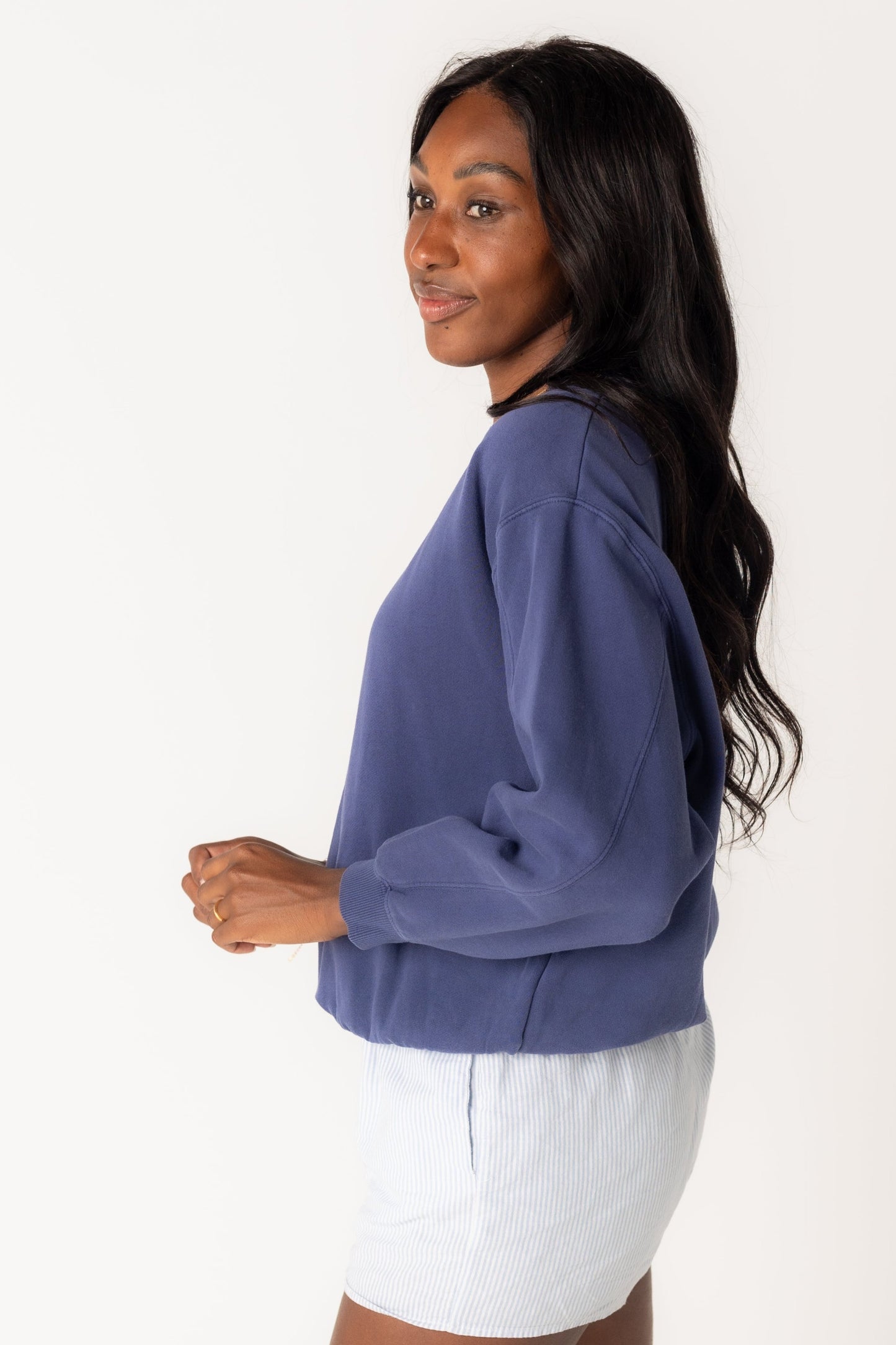 Side view of a woman wearing an navy sweatshirt by Billabong