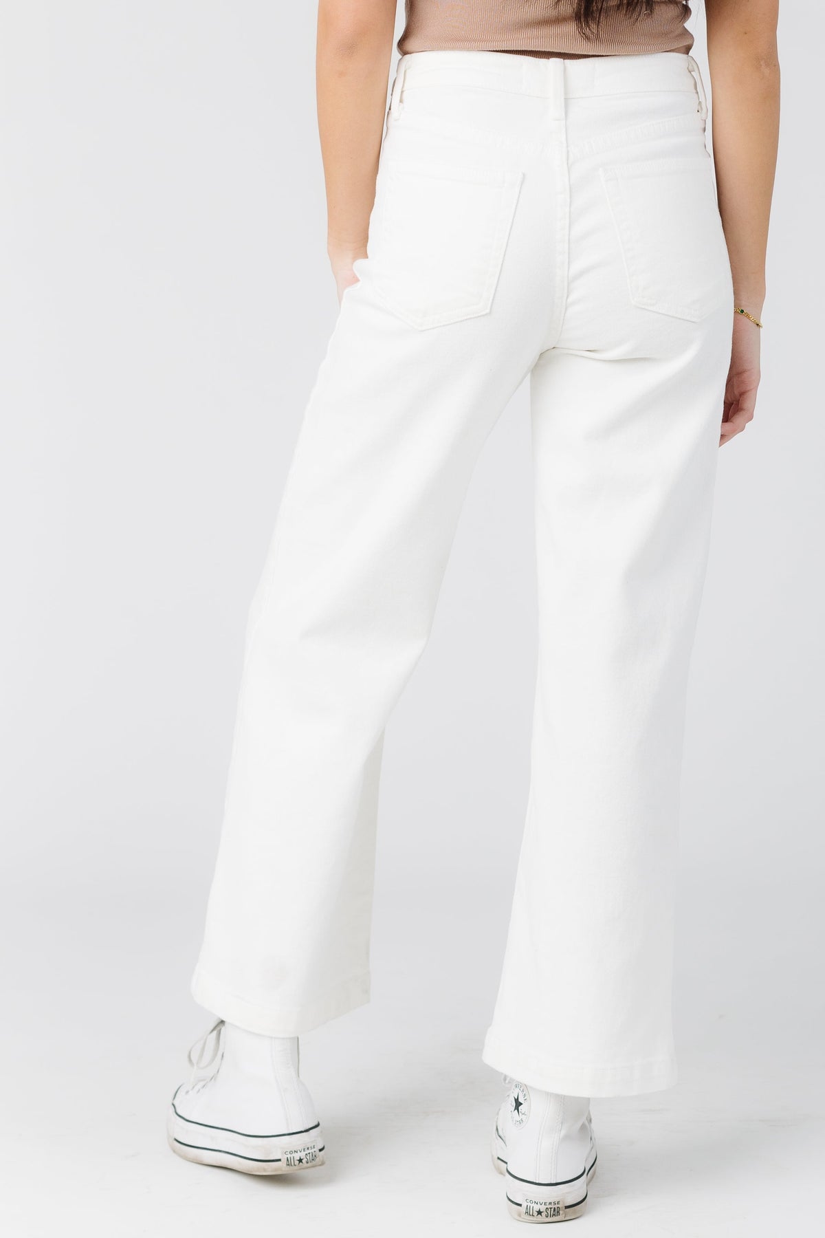Back view of a young woman wearing white straight leg jeans.