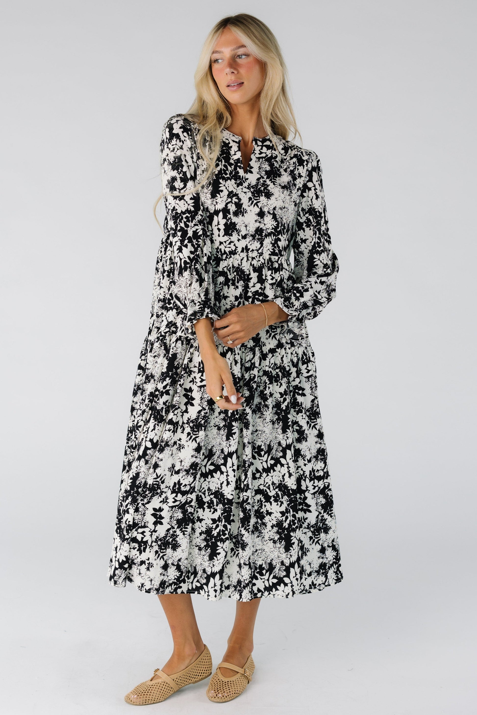 Woman wearing a black and white floral print midi dress with long sleeves
