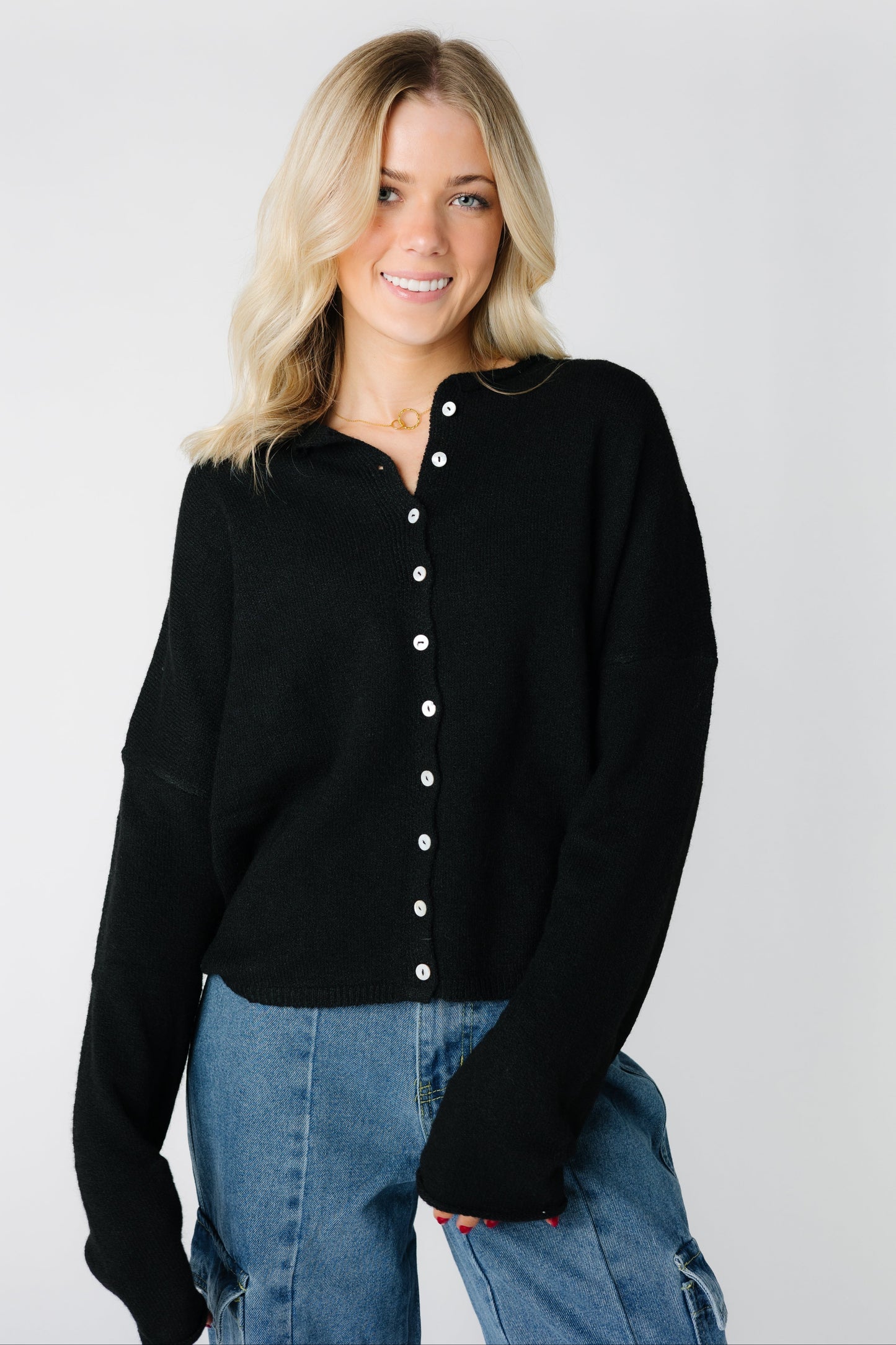 A woman wearing a black button down cardigan with long sleeves
