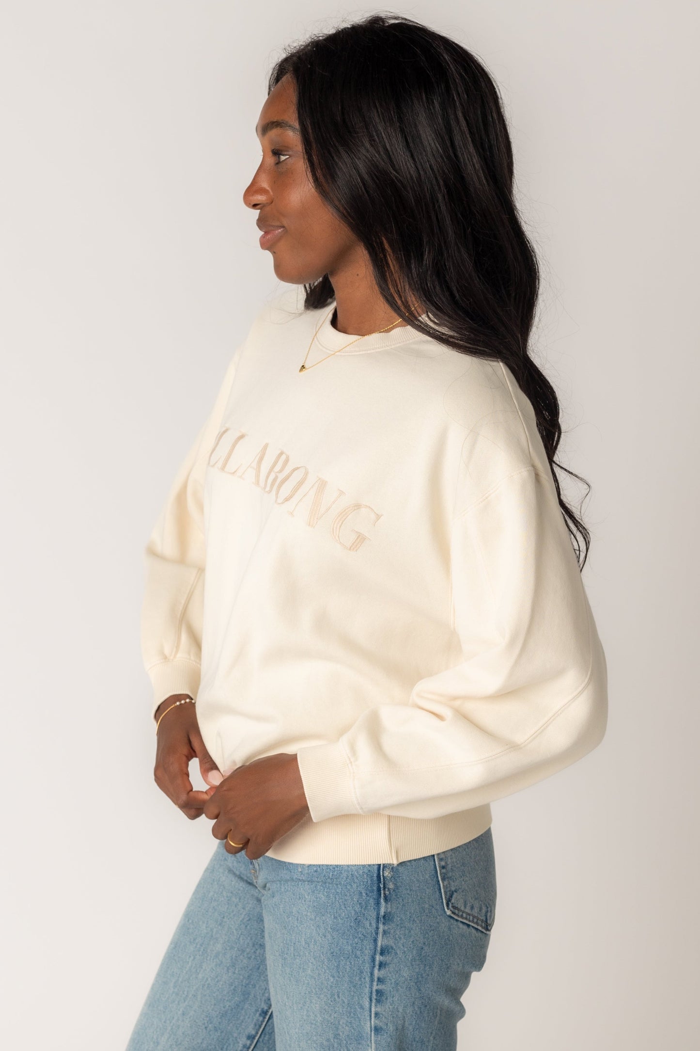Side view of woman wearing an off white long sleeve sweatshirt