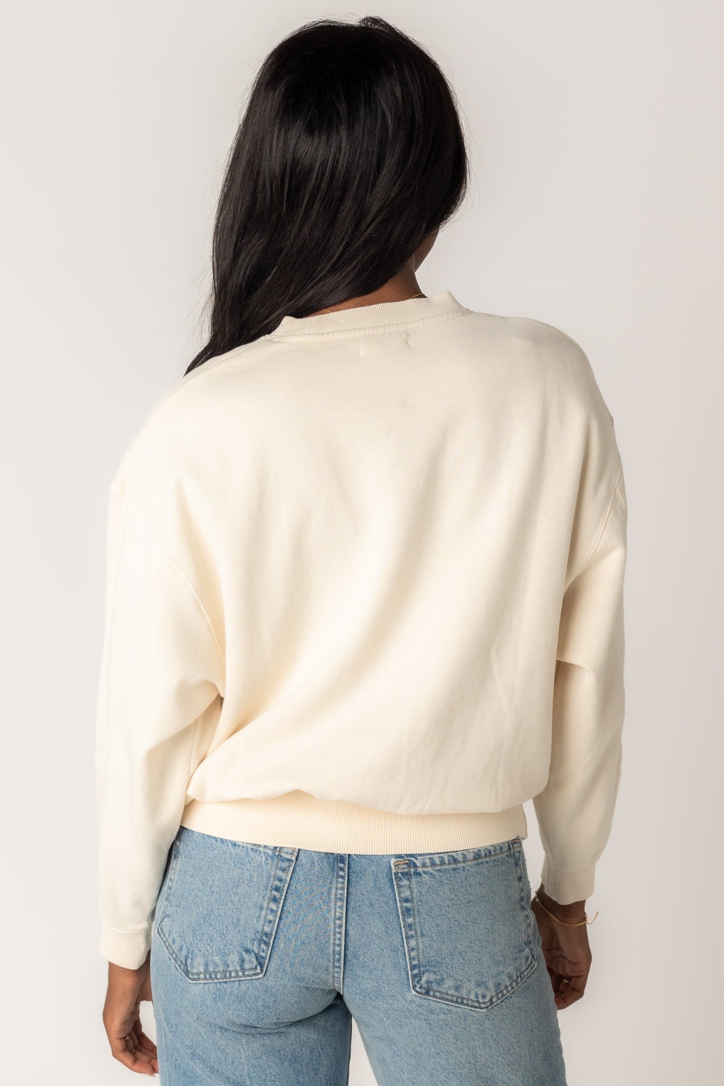 Back view of a woman wearing an off white sweatshirt