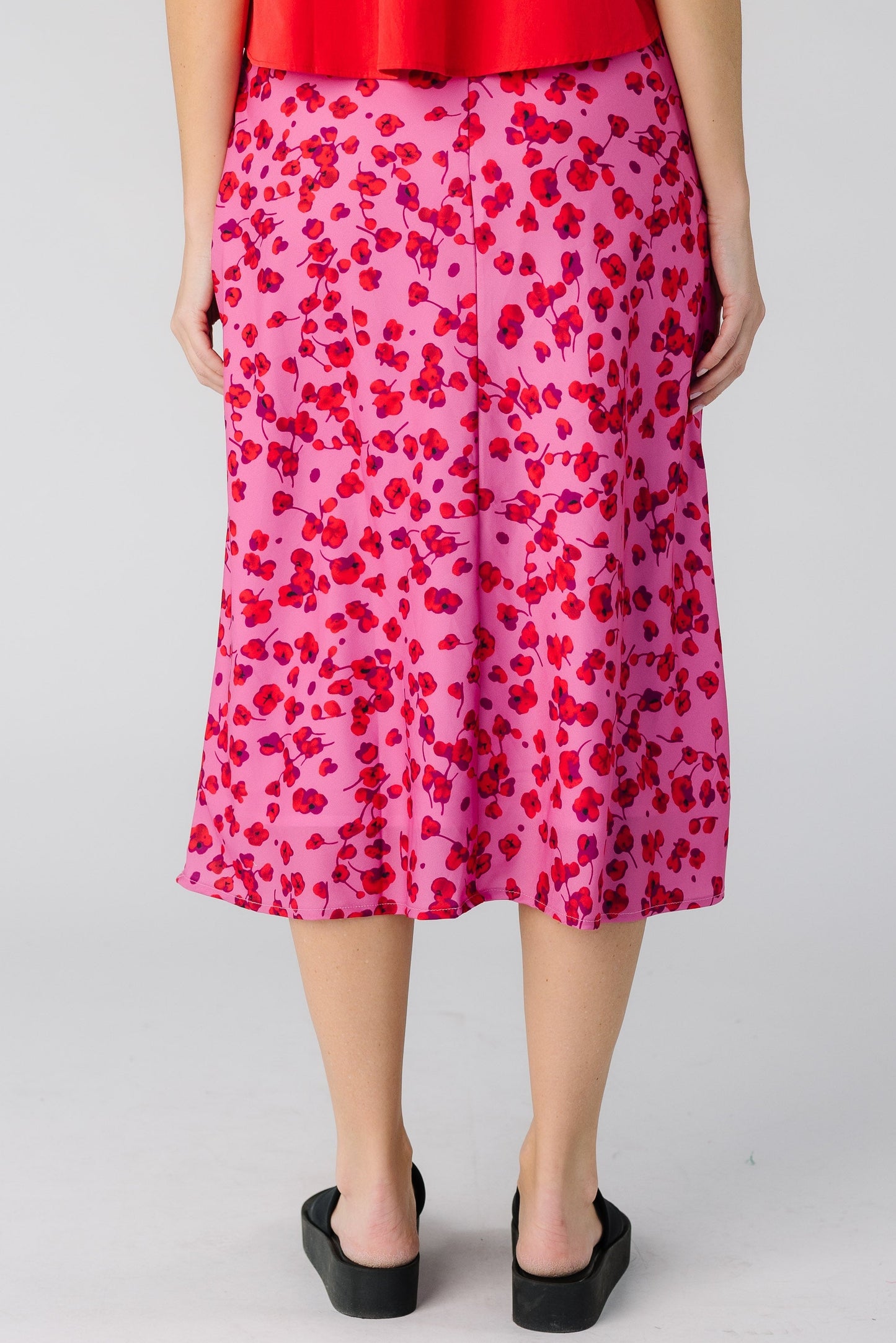 Back view of a woman wearing a pink A-line midi skirt.