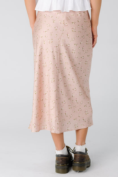 Back view of a woman wearing a pink floral midi skirt.