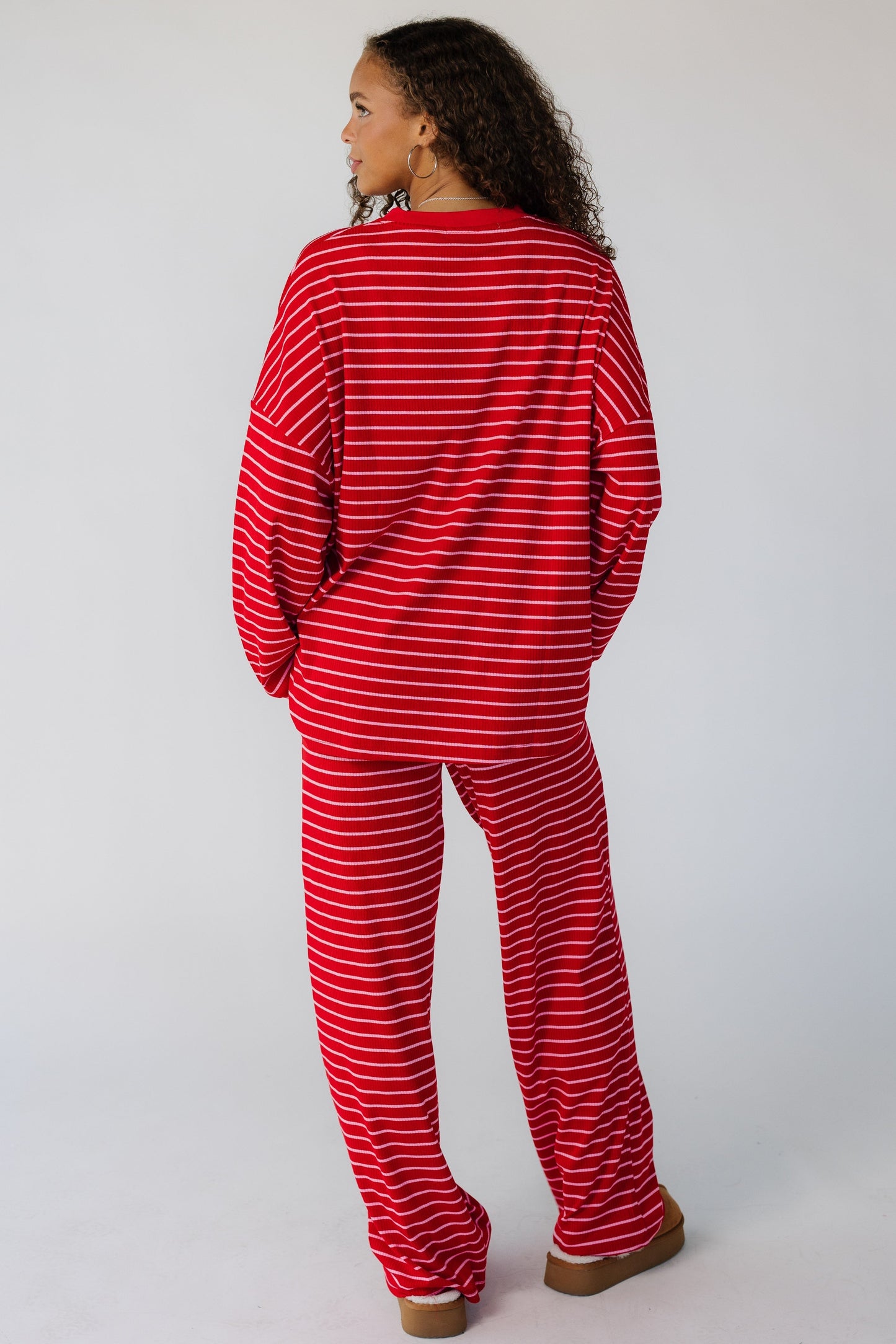 Back view of a teen wearing a 2 piece red stripe lounge set with long pants and long sleeves.