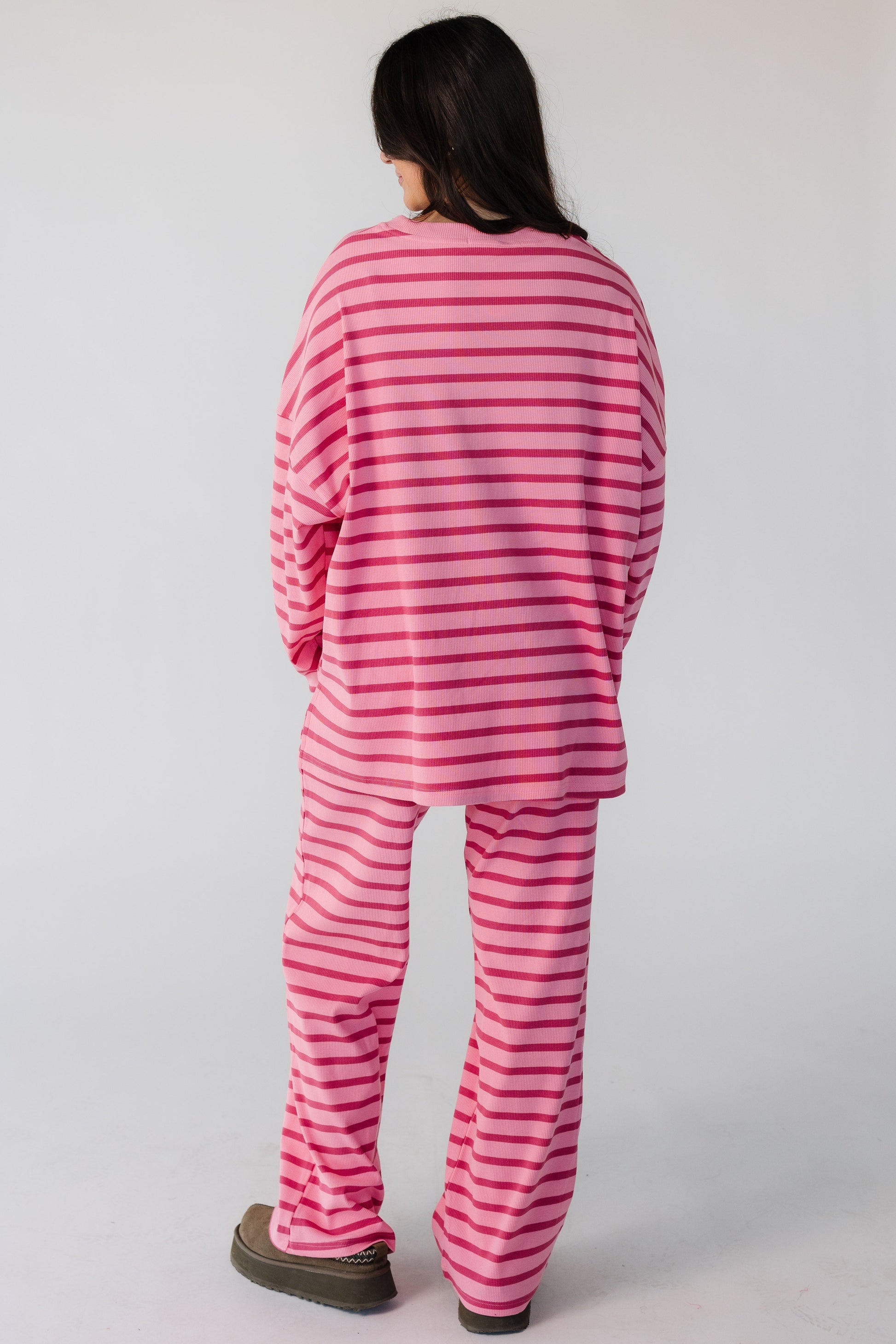 Back view of a woman wearing a pink ribbed lounge set with mauve stripes.