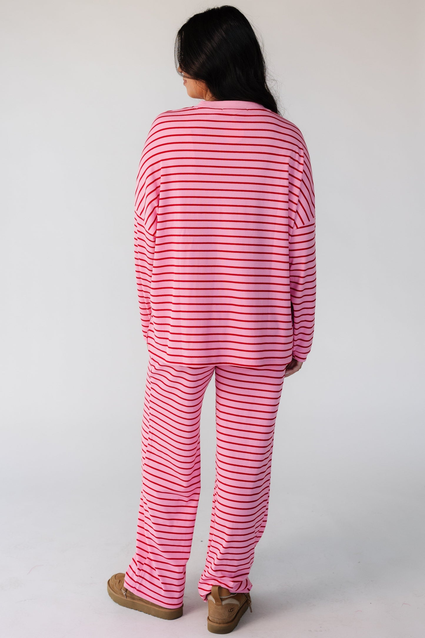Back view of a woman wearing a pink ribbed lounge set with long sleeves and long pants.