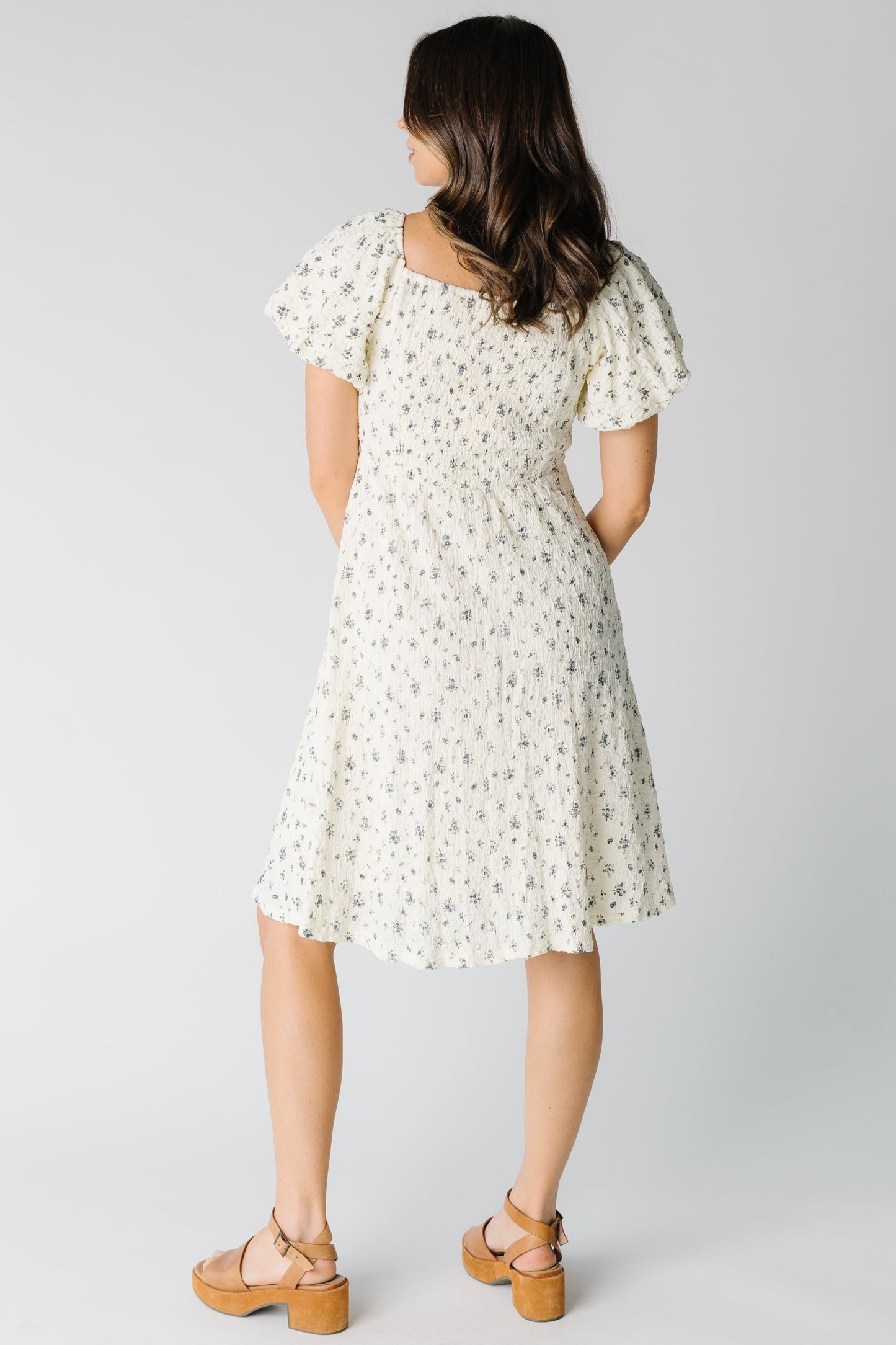 Back view of ivory dress with blue floral print and short puff sleeves