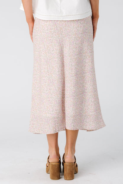 Back view of a woman wearing a light pink floral skirt in midi length.