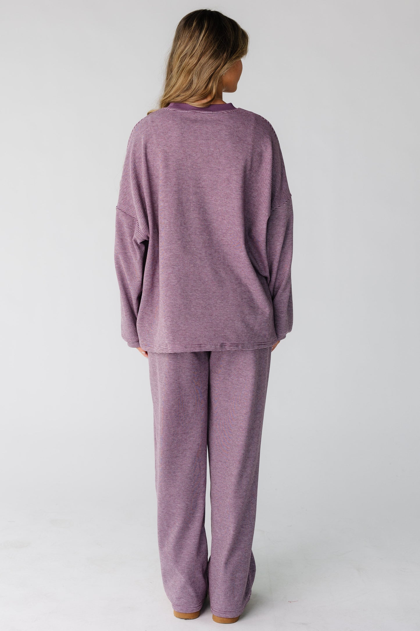 Back view of a woman wearing a loose fitting lounge set in berry purple.