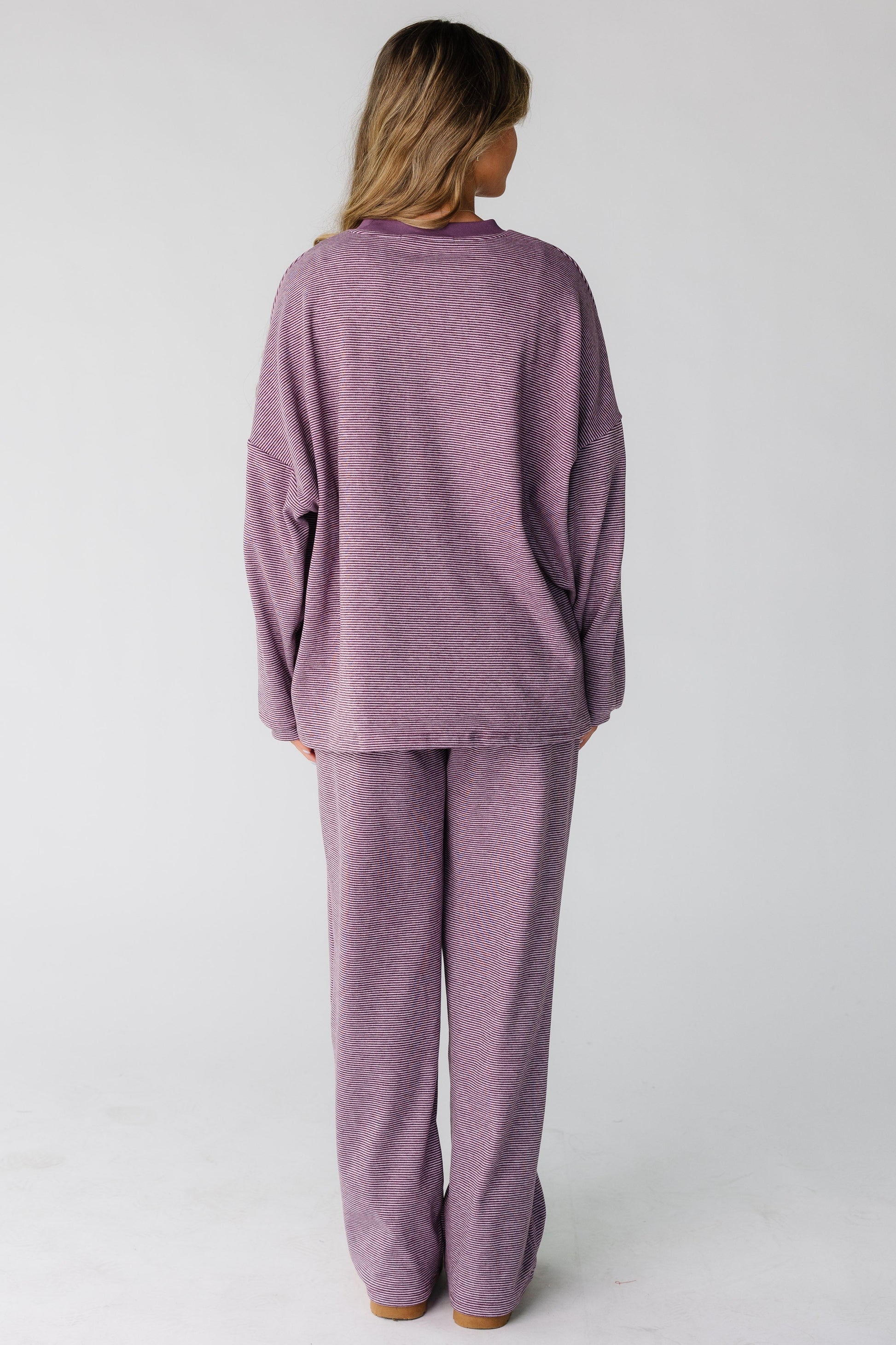 Back view of a woman wearing a loose fitting lounge set in berry purple.